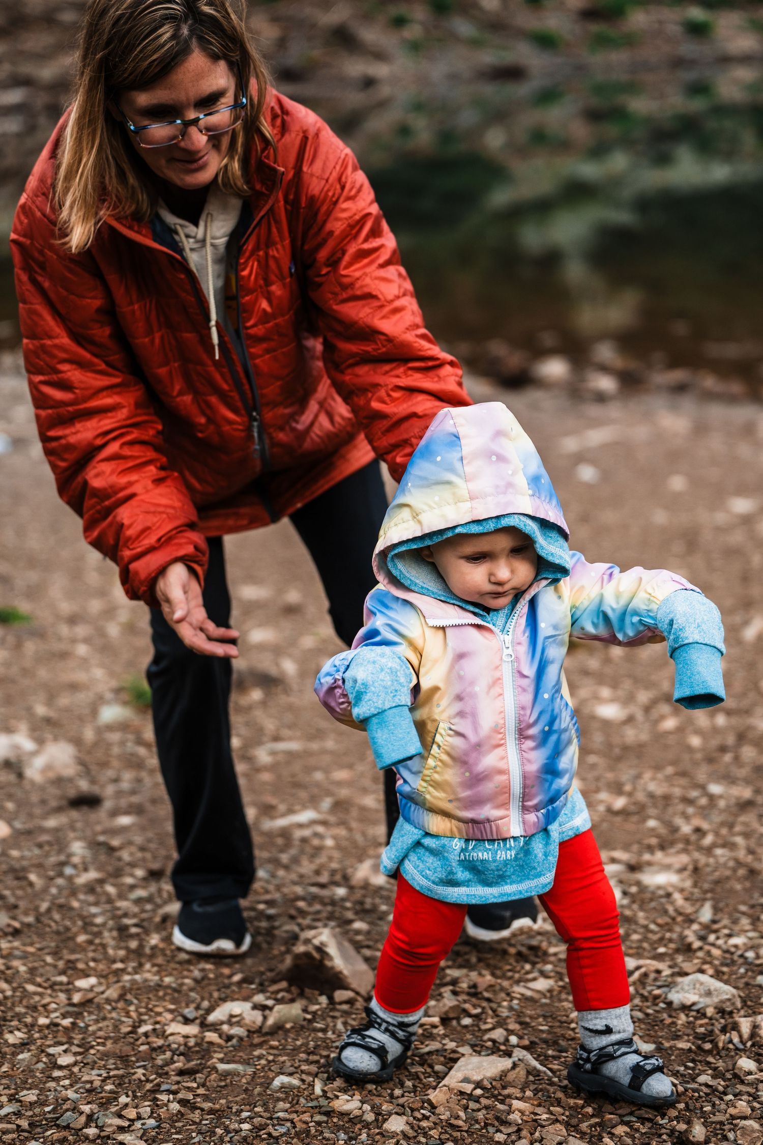 A heartwarming outdoor moment with a child taking first steps in colorful winter gear.