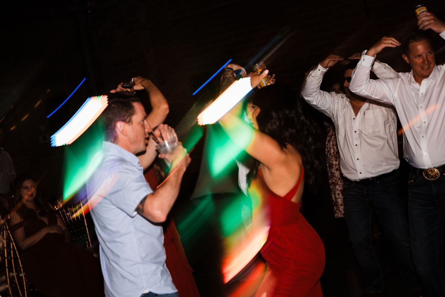 People dancing and celebrating at a party with colorful lighting effects in motion.