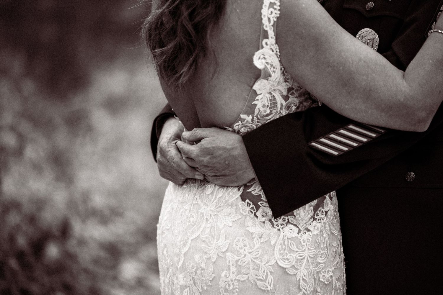 Close-up details of an elegant lace wedding dress against a dark background.