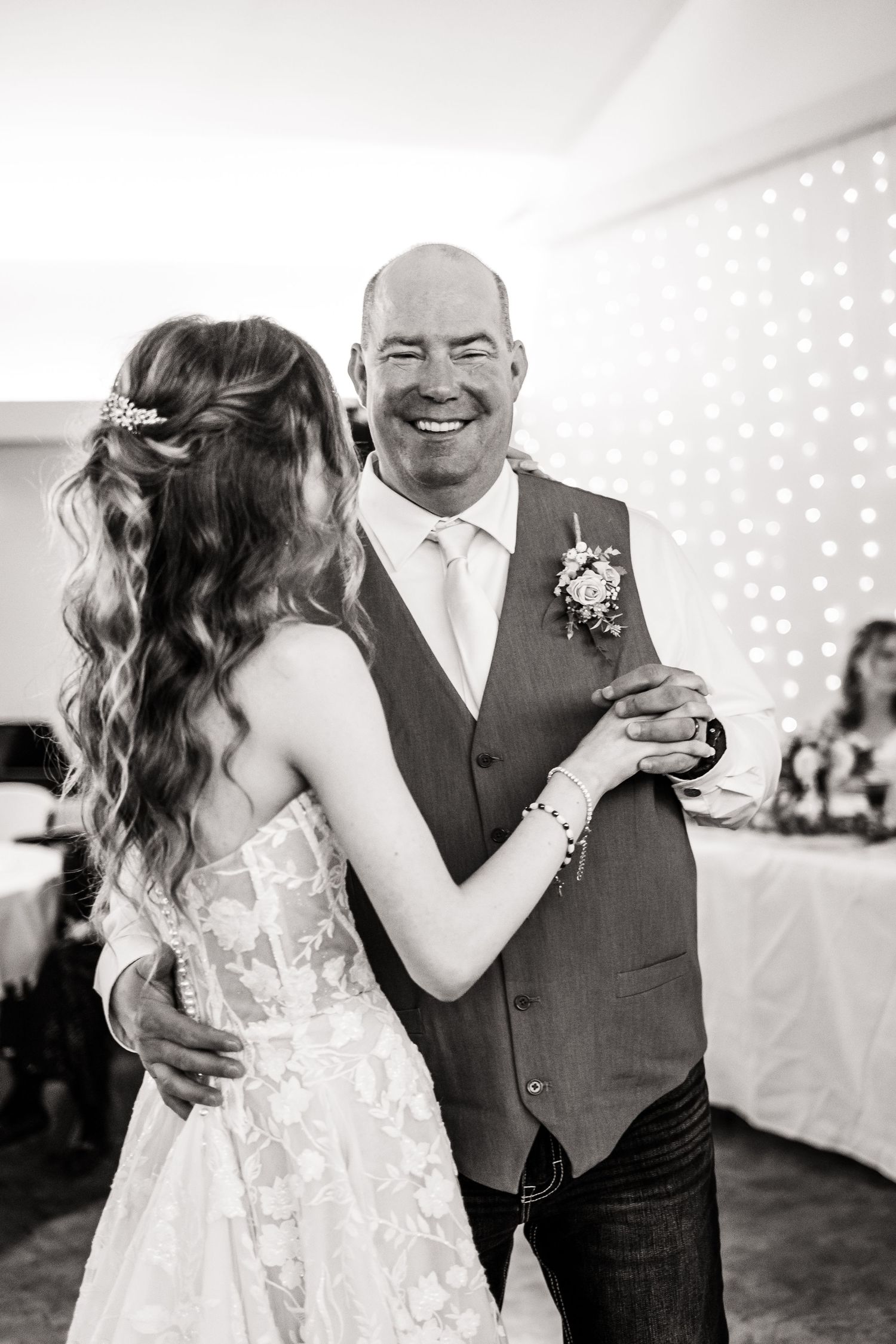 A tender father-daughter dance moment captured in black and white at a wedding reception.