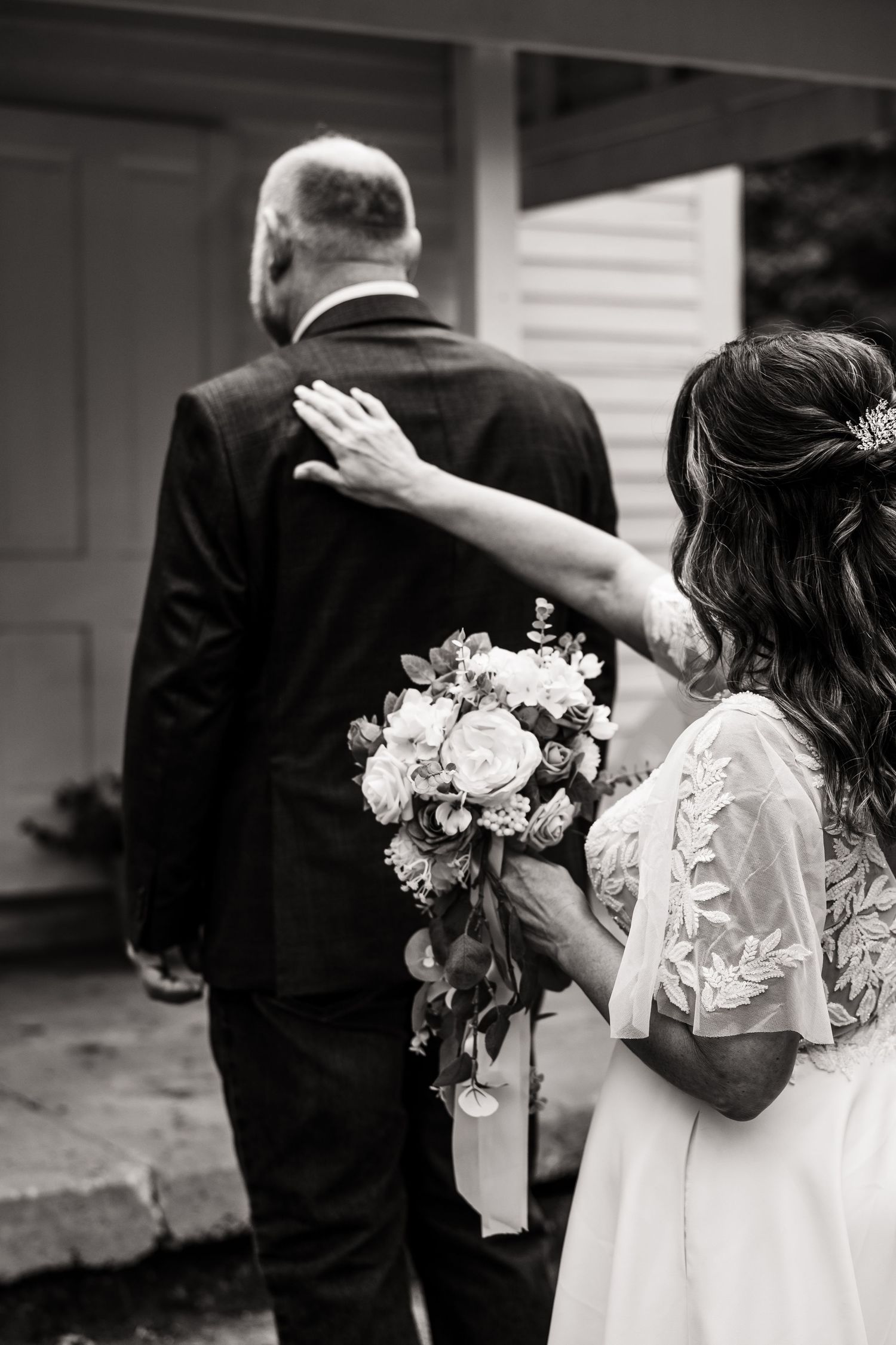 A bride holds a beautiful bouquet of roses and delicate flowers as she walks with her partner.