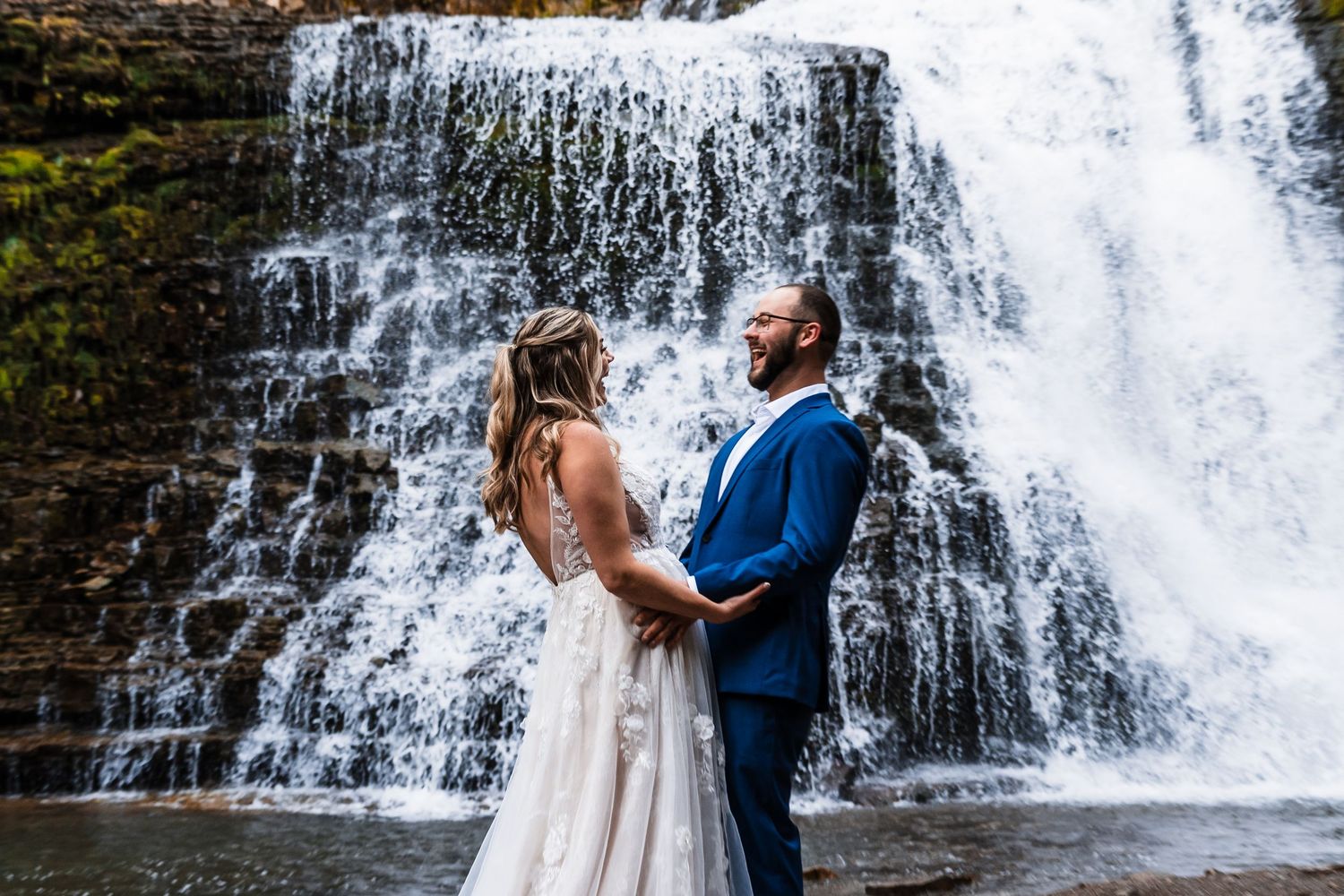 A couple sharing a romantic moment in front of a cascading waterfall.