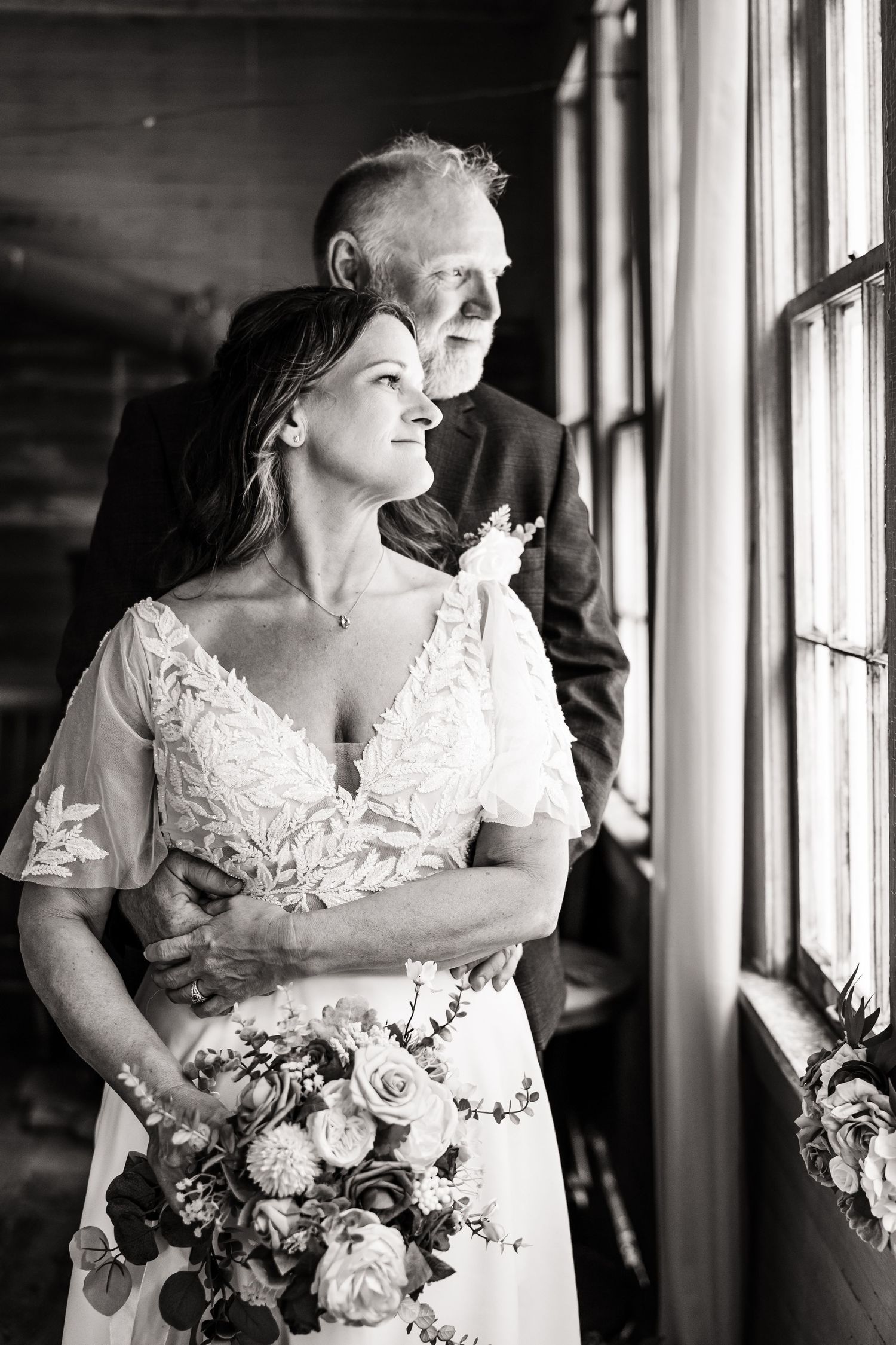 Artistic black and white bridal portraits near windows with natural light and floral bouquet.