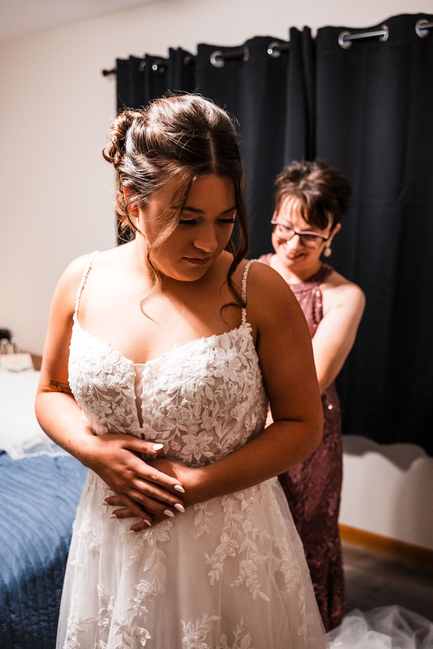 Close-up shots of intricate lace detailing on a white wedding gown during preparation.