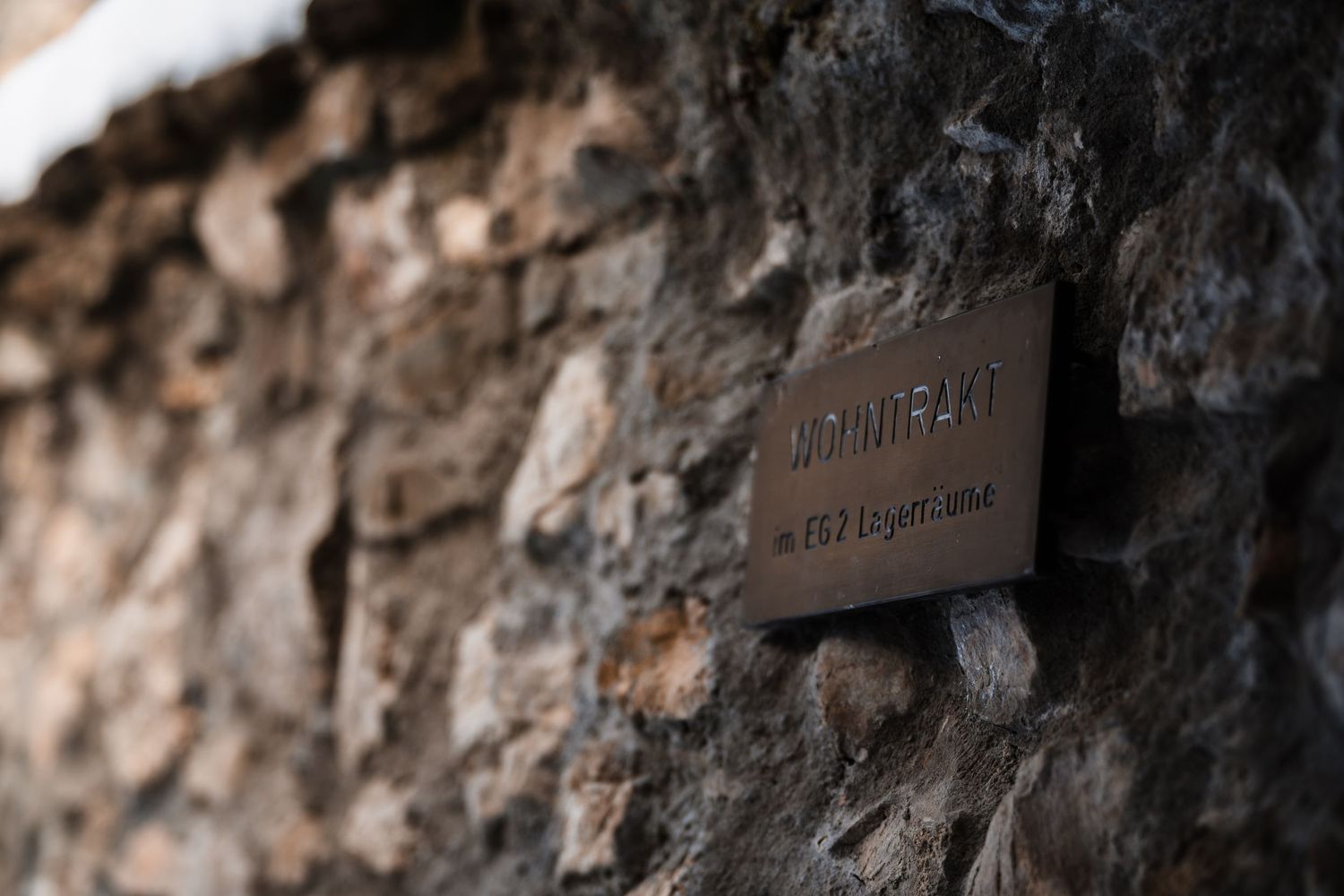 Close-up view of weathered stone wall texture with snow dusting in mountain setting.