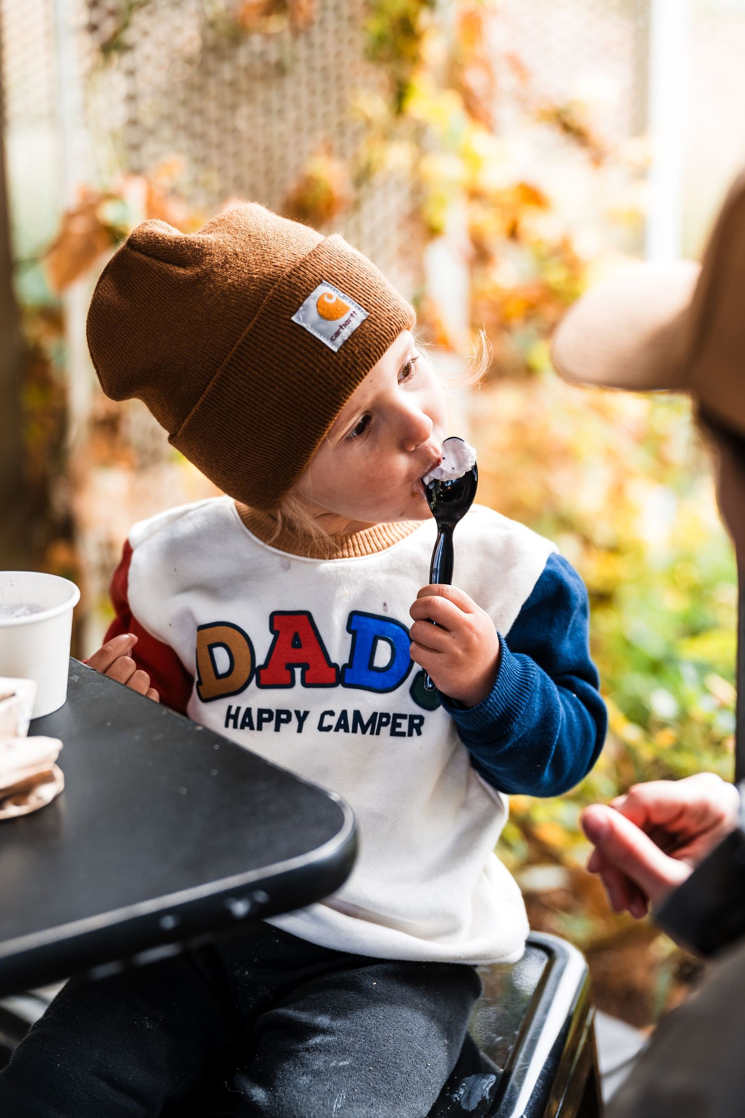 A series of photos showing a small child in a brown beanie and white shirt enjoying snacks in autumn lighting.
