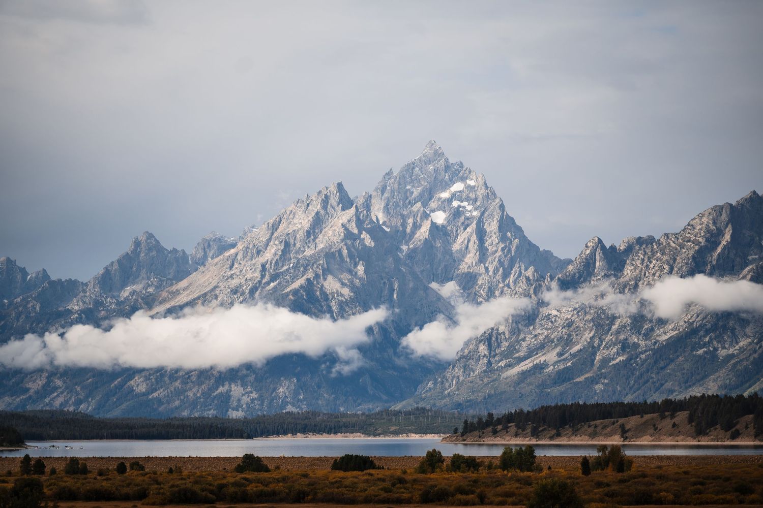 Panoramic view of jagged mountain peaks with low clouds in Grand Teton National Park.