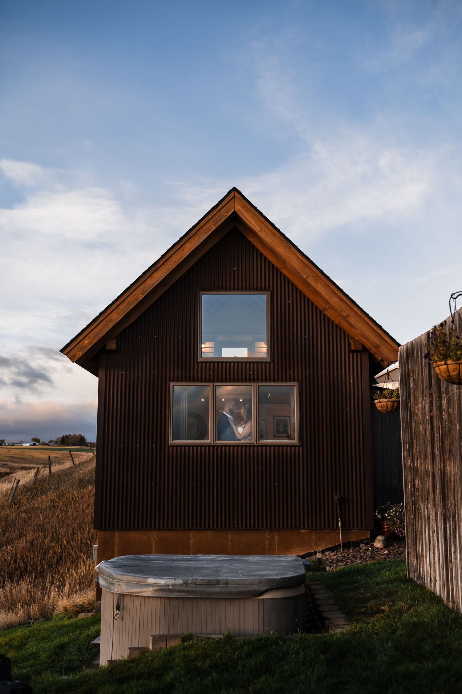 Dark wooden cabins with angular rooflines sit against a cloudy sky in a rustic outdoor setting.
