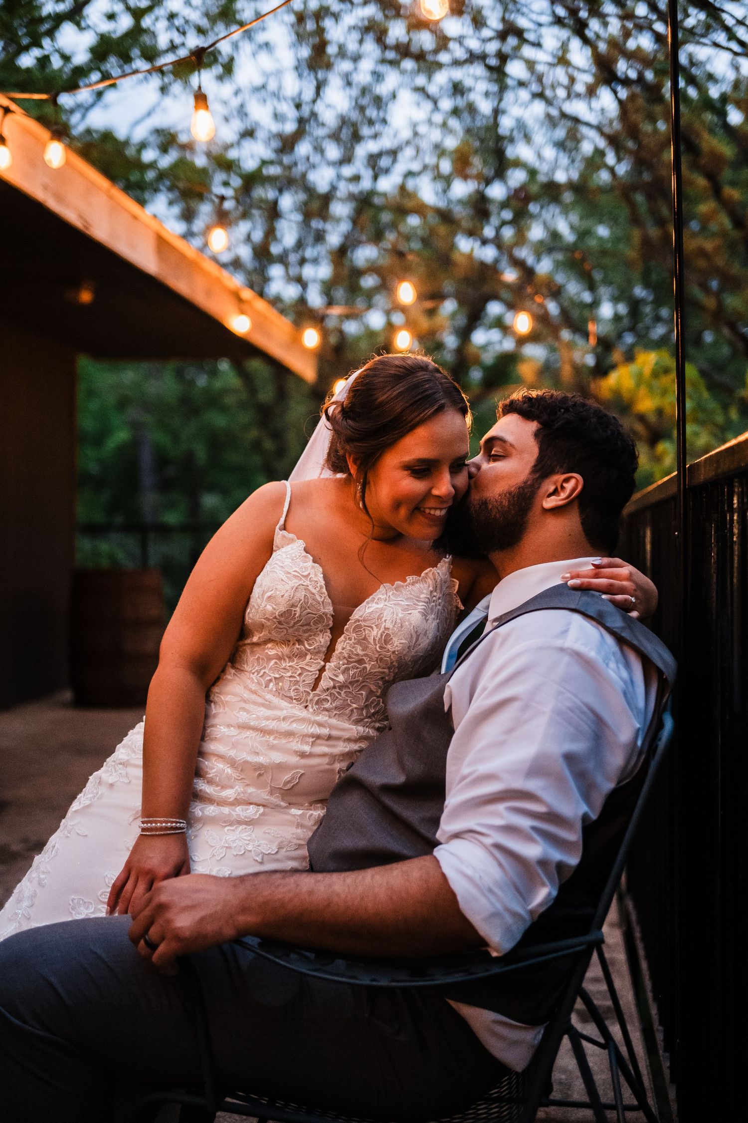Romantic moment between newlyweds sharing an intimate embrace on a porch swing at dusk.