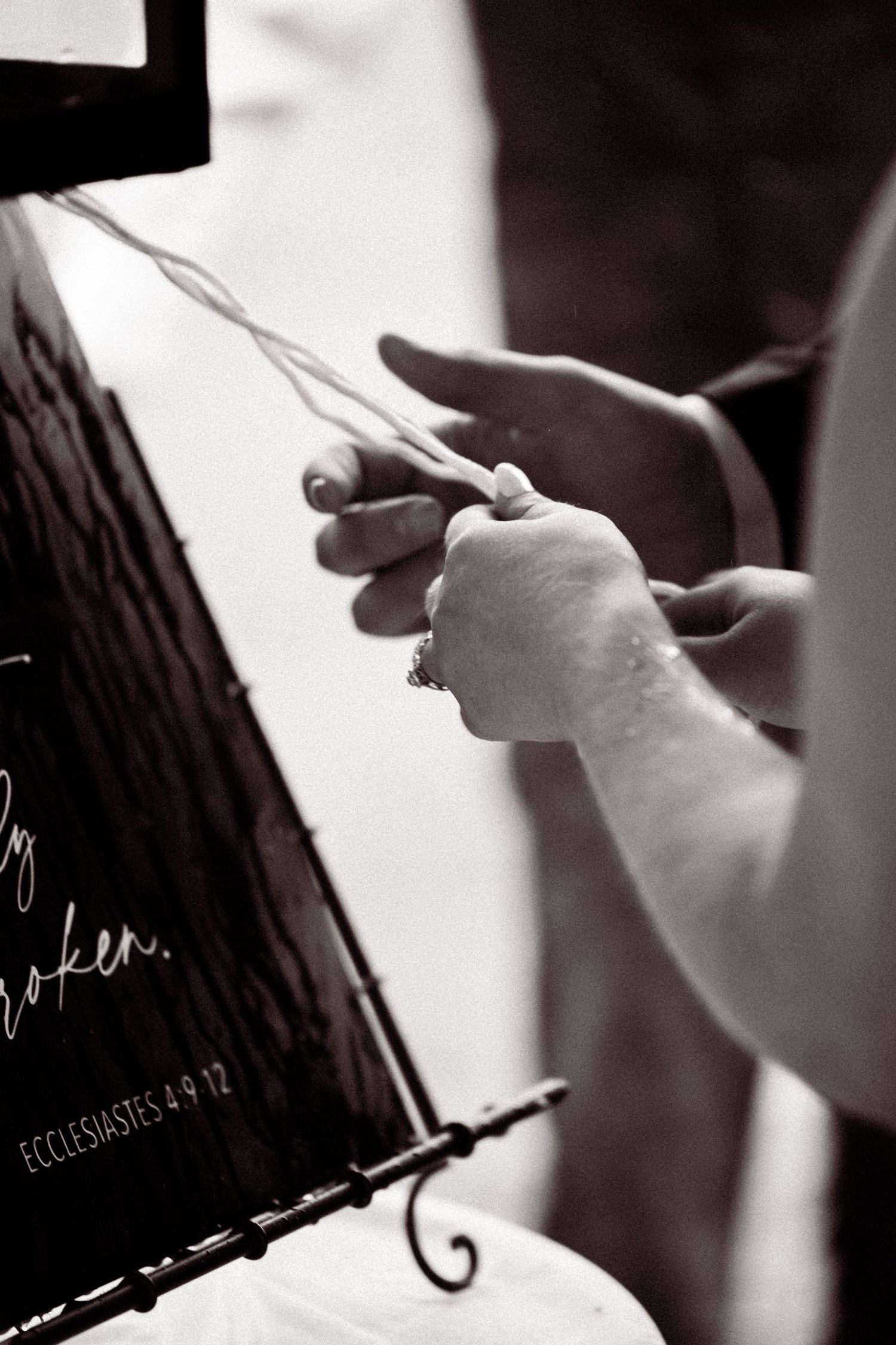 Close-up sequence of hands signing a document with a pen in black and white.