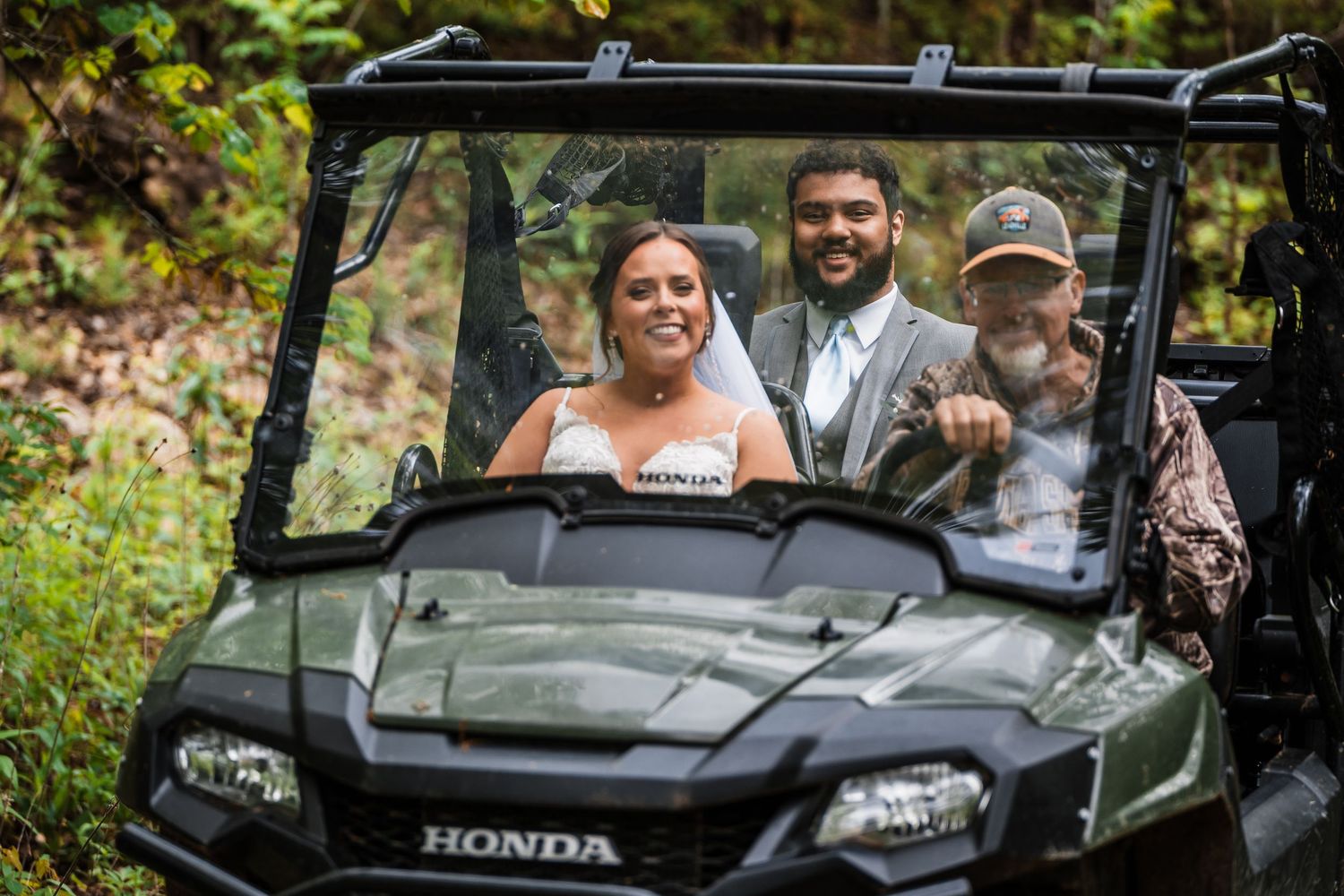 Wedding couple riding in a green Honda UTV through nature.