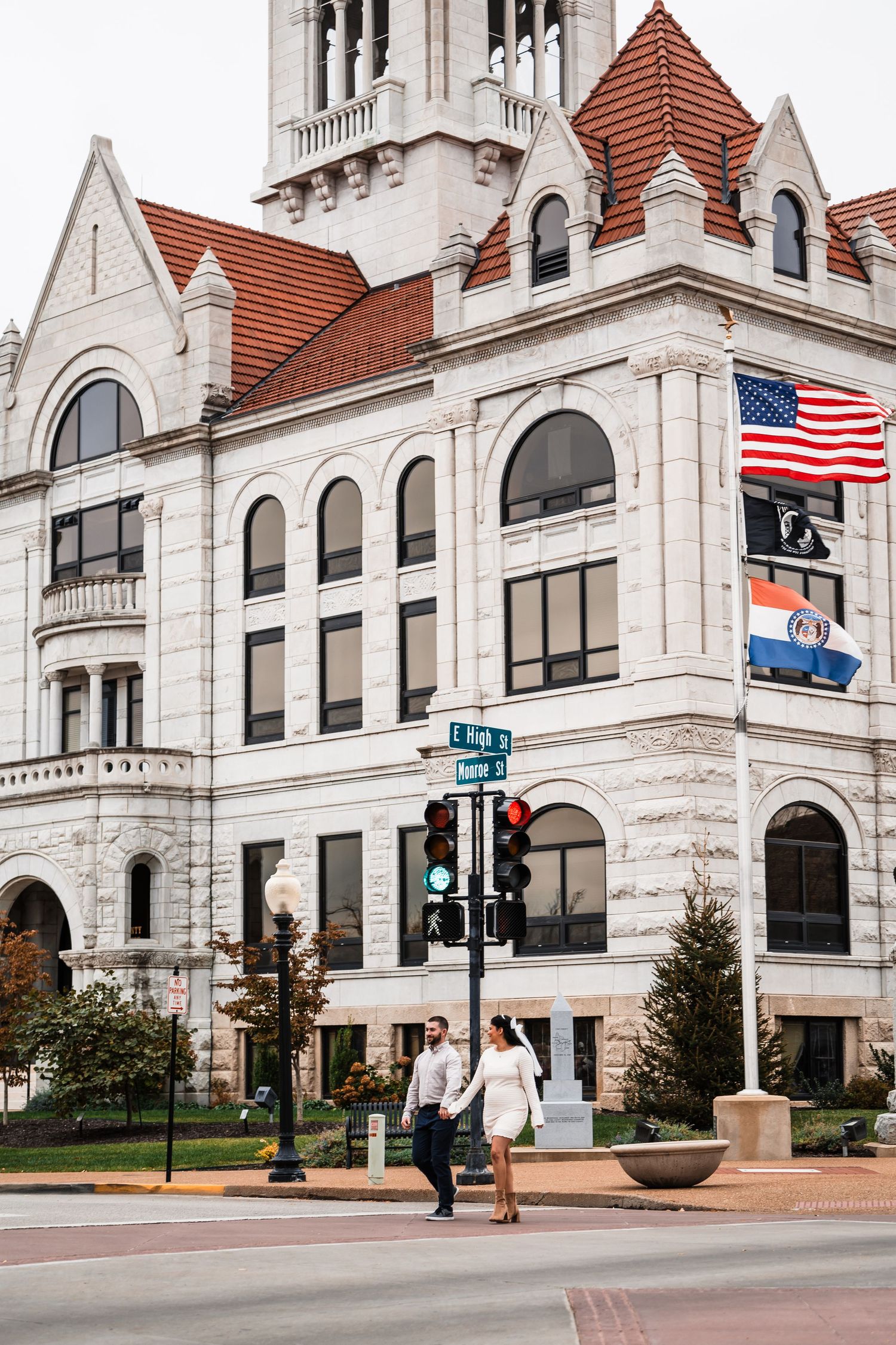 A historic white stone courthouse building with red roof tiles and an American flag.