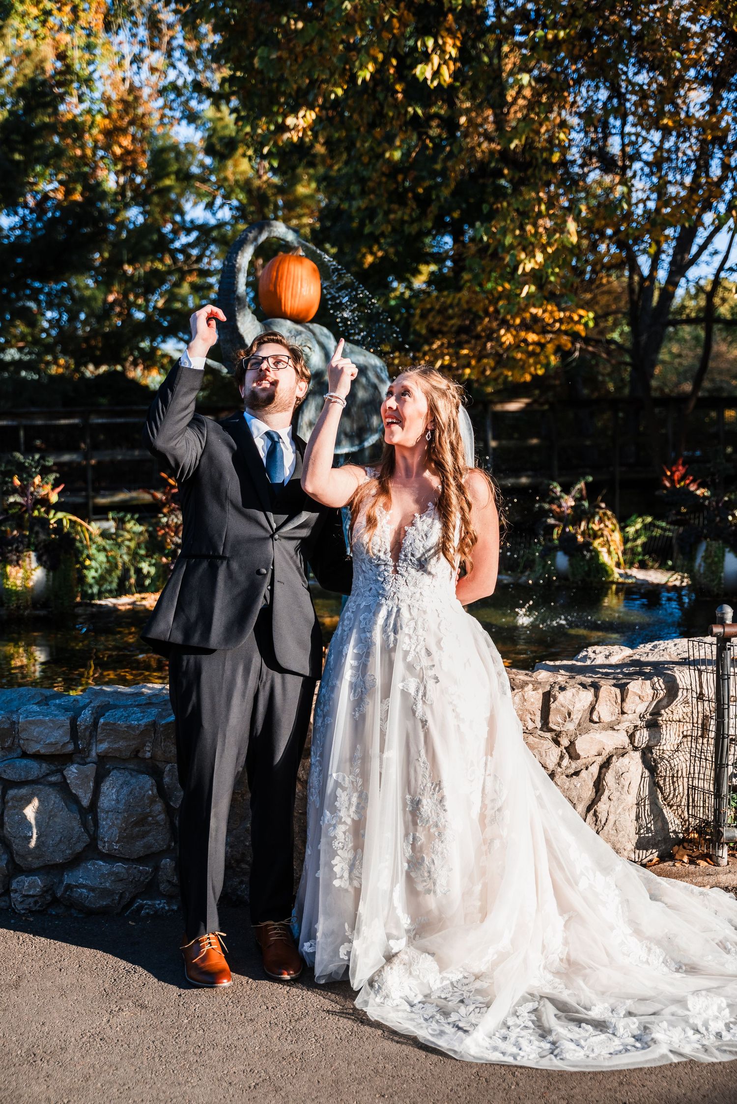 Playful couple holds pumpkins during autumn wedding photoshoot.