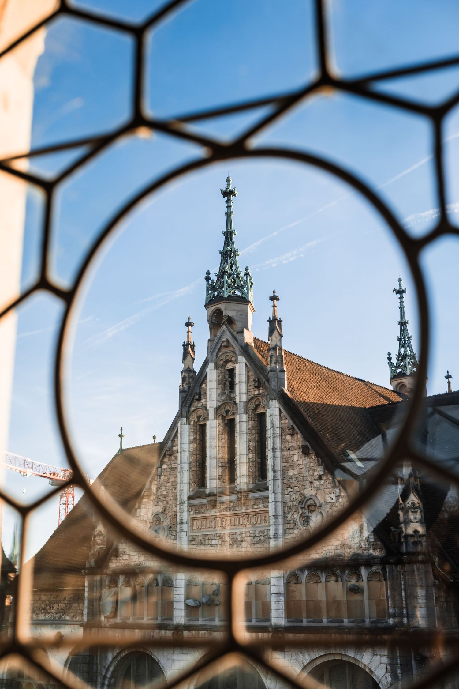 Gothic church spires and ornate architecture viewed through decorative stained glass window frames.