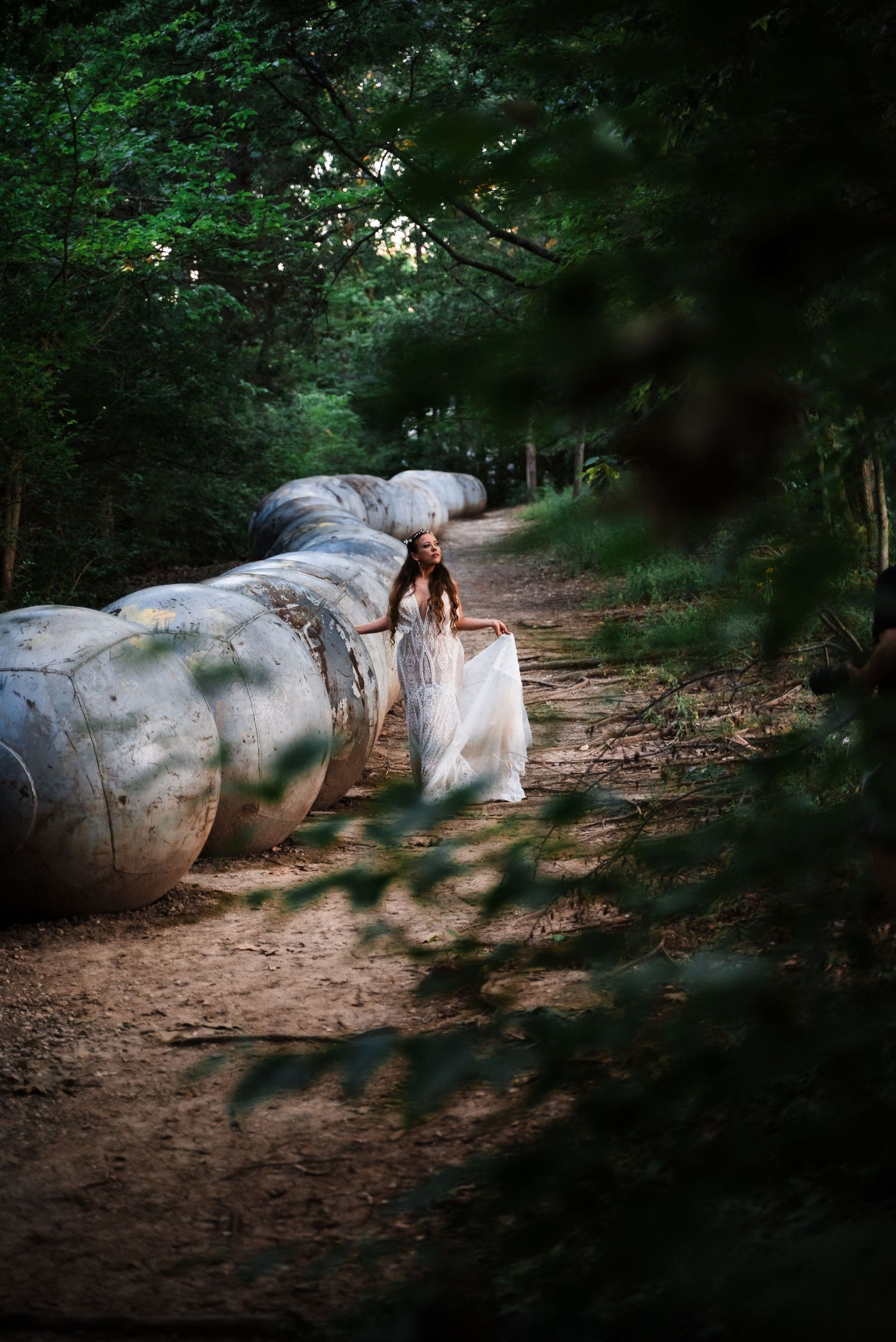 A figure in white lies gracefully on large boulders along a forest path in a dreamy outdoor setting.