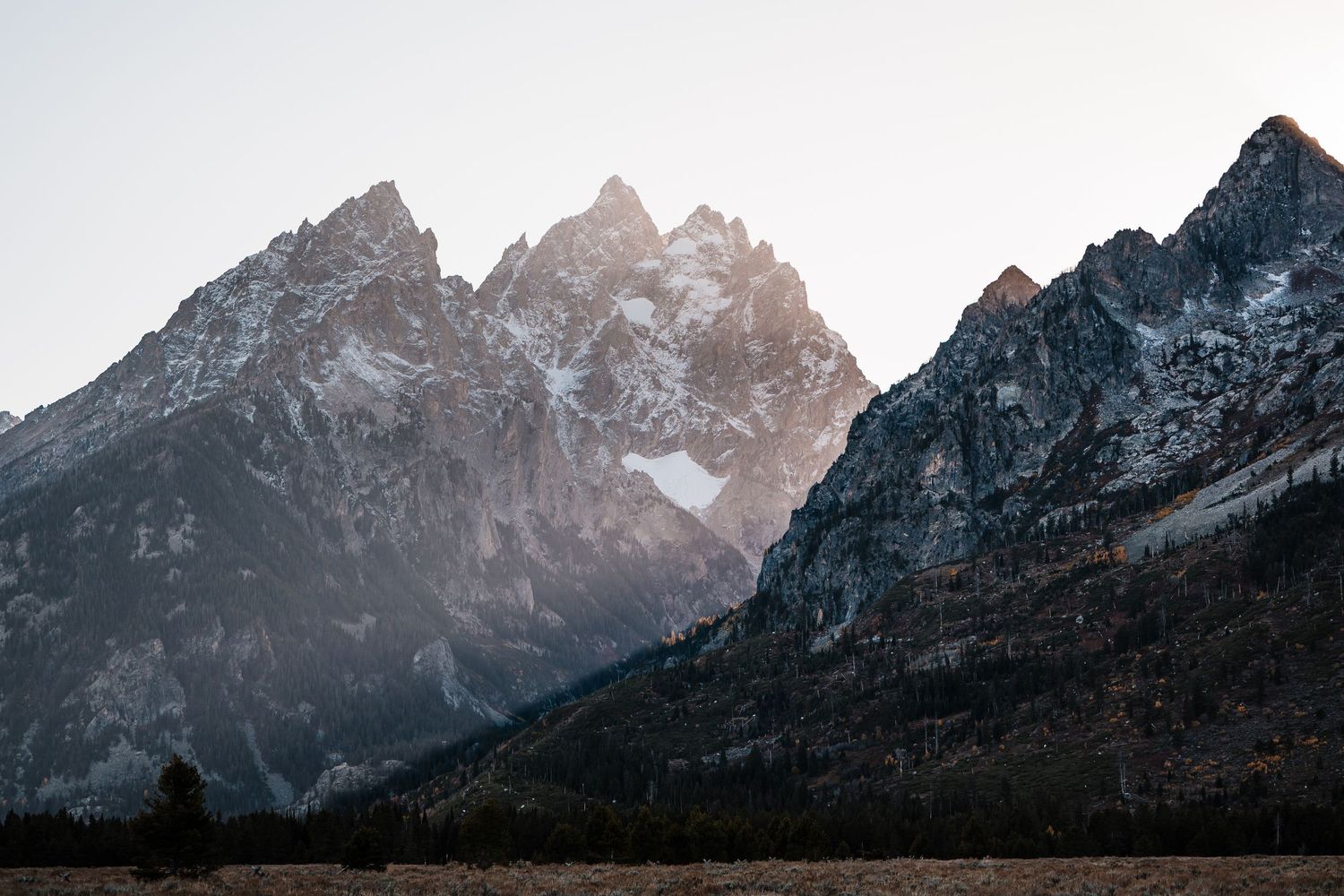 Dramatic mountain range silhouettes against a bright sky at sunset.