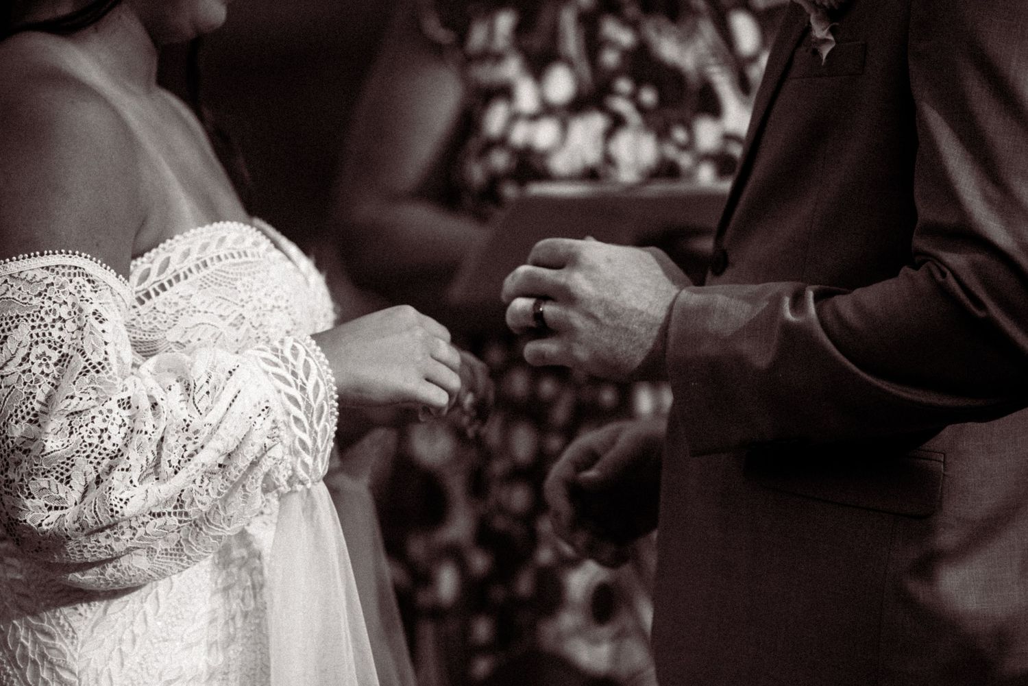 Black and white detail shot of delicate lace wedding dress fabric with intricate beading and embroidery patterns.