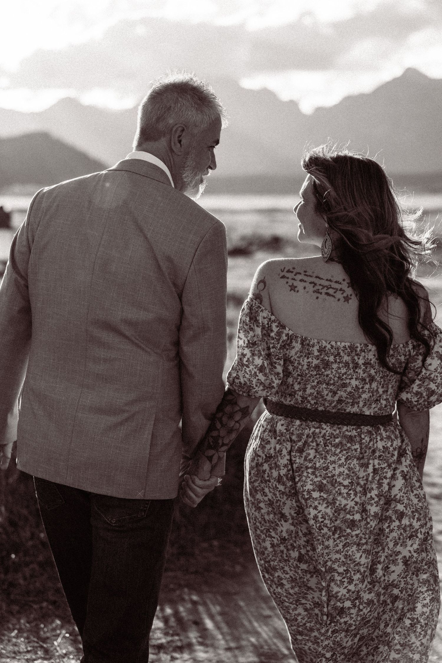 A couple walking together on a beach at sunset in black and white, shown in a series of romantic candid shots.