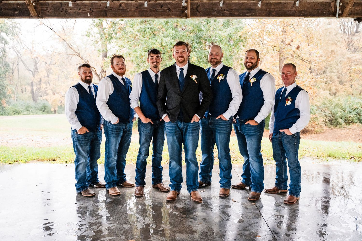 Groomsmen in matching blue jeans and suits posing together outdoors.