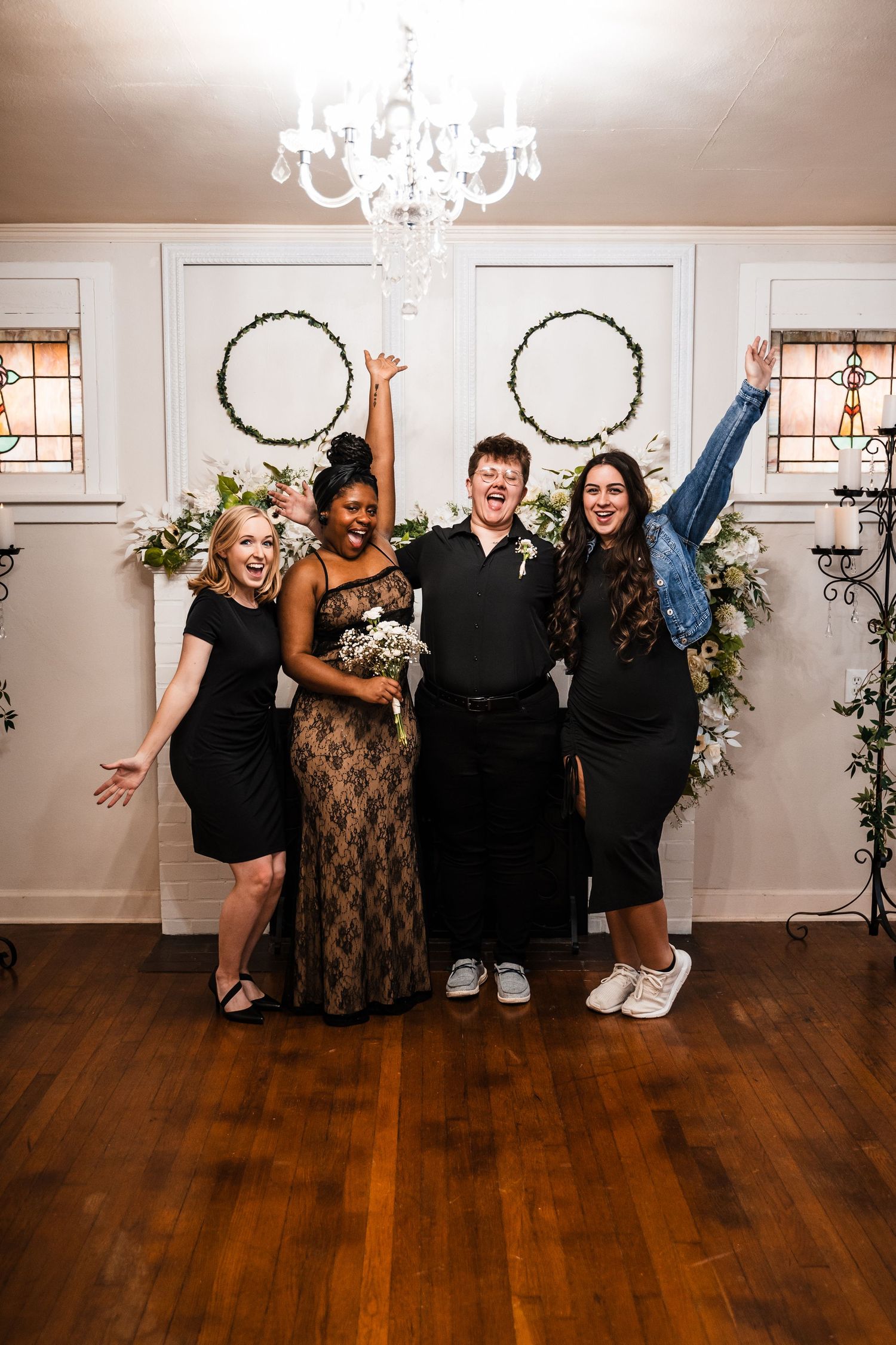 Friends celebrating joyfully after a wedding ceremony in front of floral-decorated white doors.
