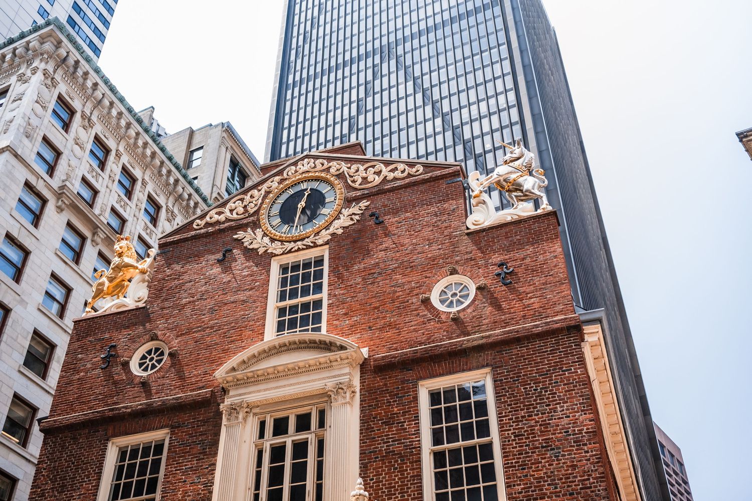 Historic red brick facade of Boston's Old State House with ornate architectural details against modern glass skyscrapers.