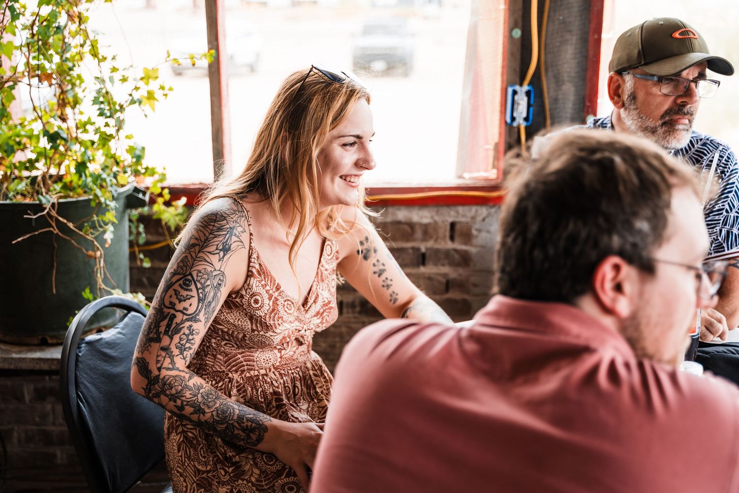 Customers enjoying conversation at rustic cafe tables with red cups and natural lighting.