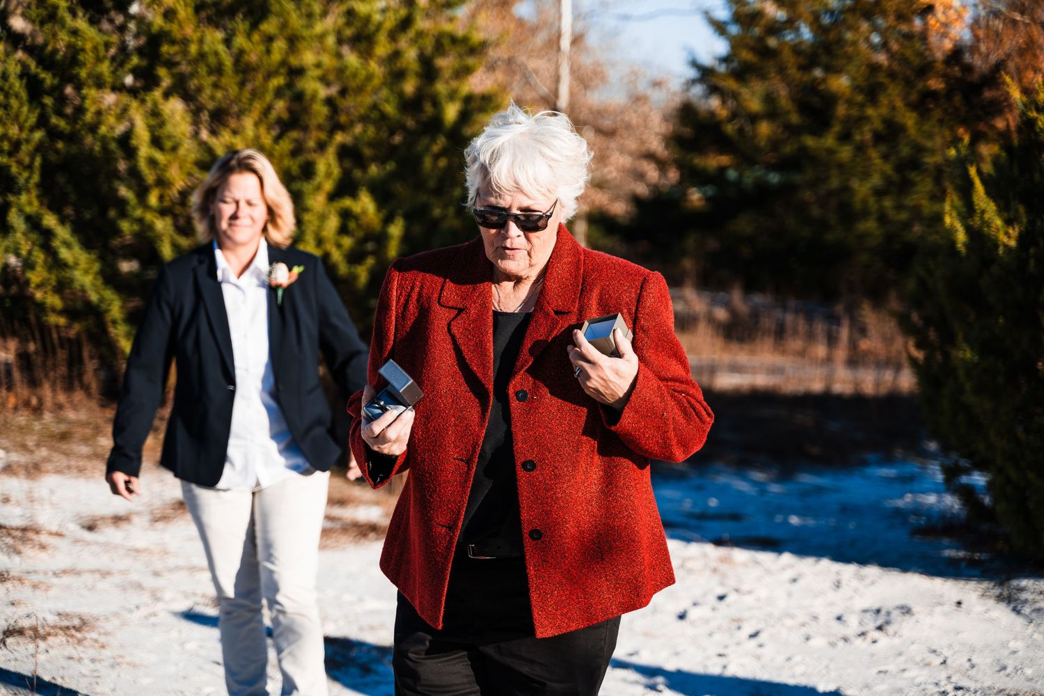People outdoors in winter clothing with person in bright red jacket holding phones.