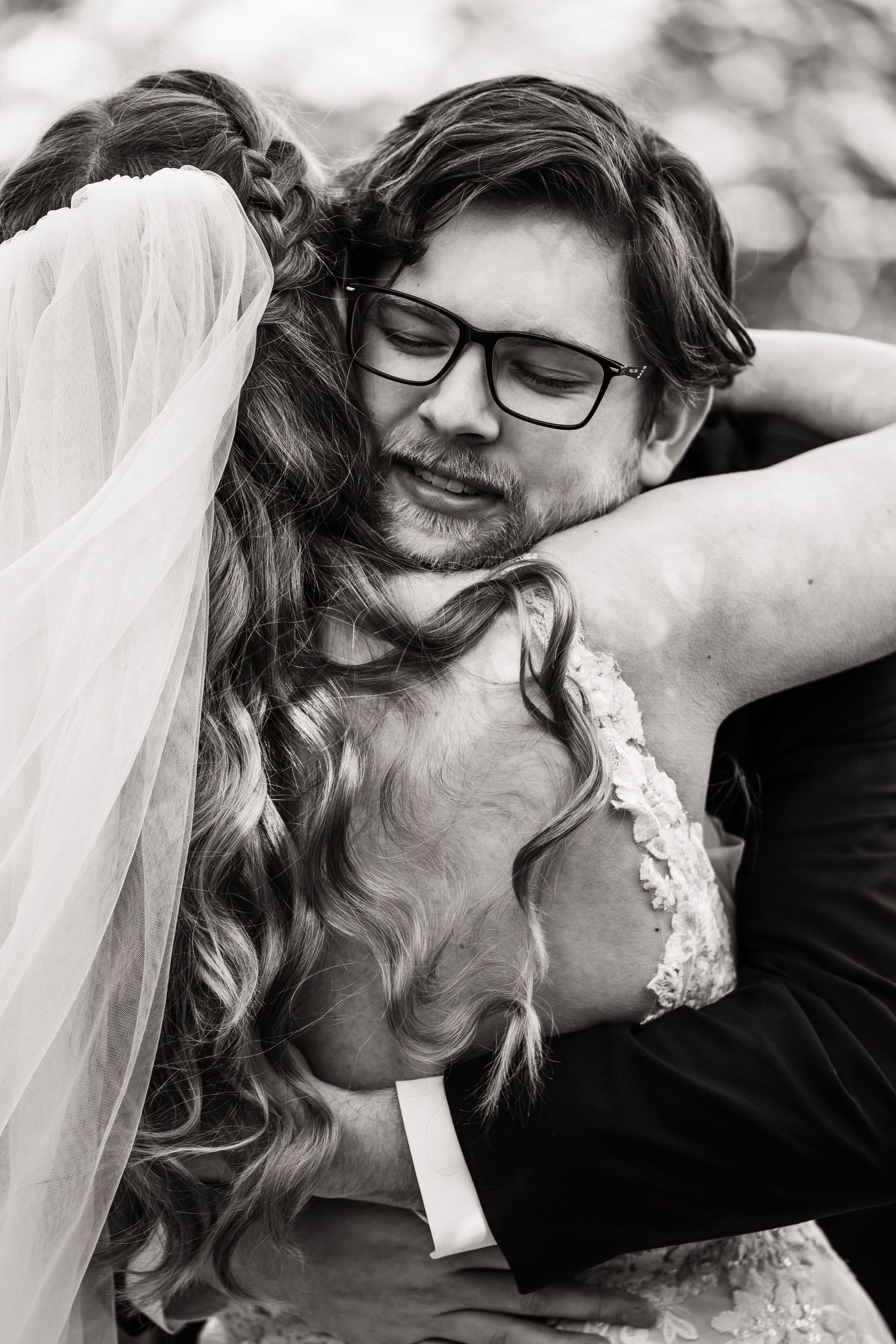 Intimate black and white portrait of newlyweds embracing during outdoor wedding.