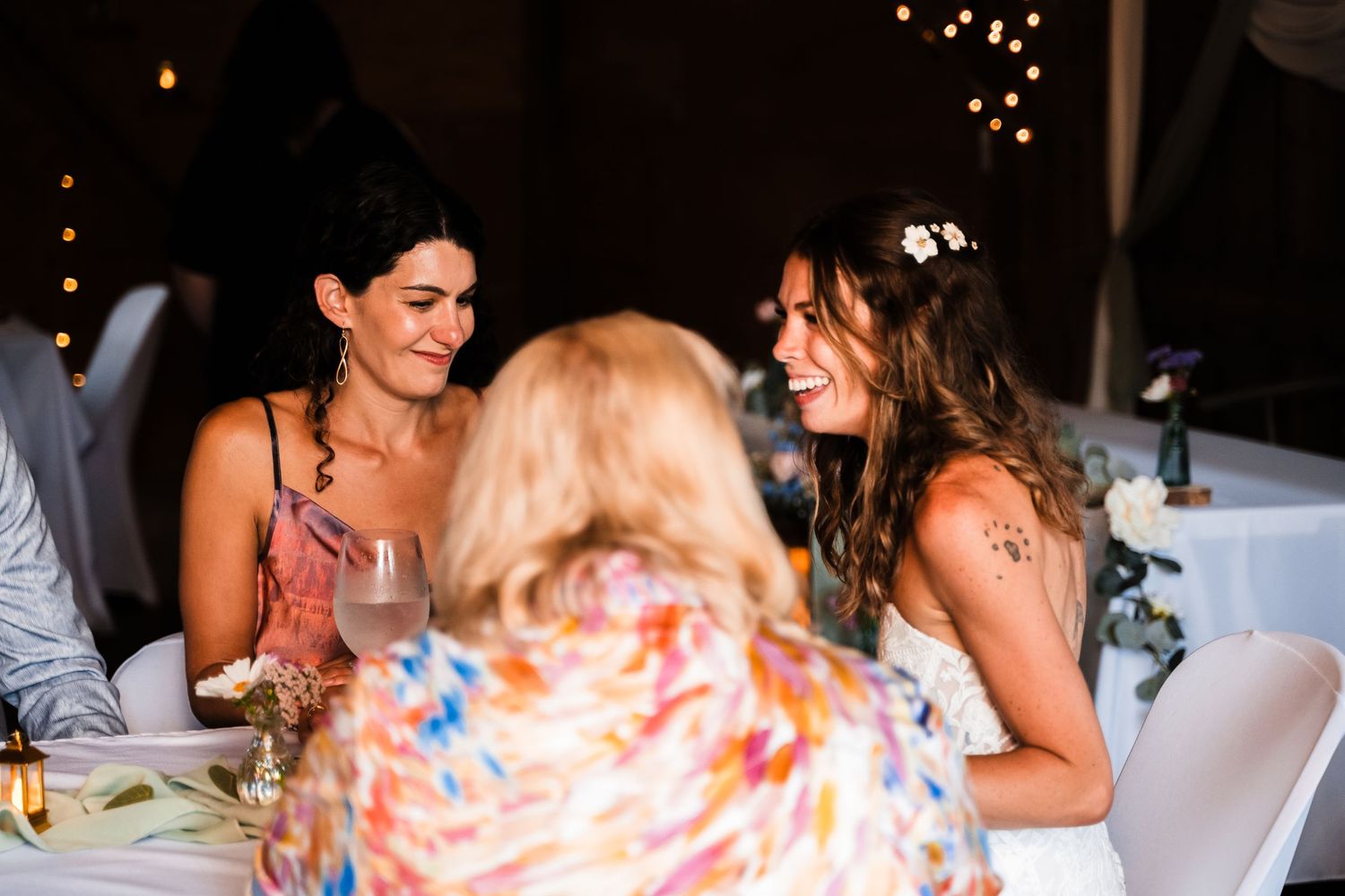 Wedding guests enjoying conversation and laughter at a decorated reception table.