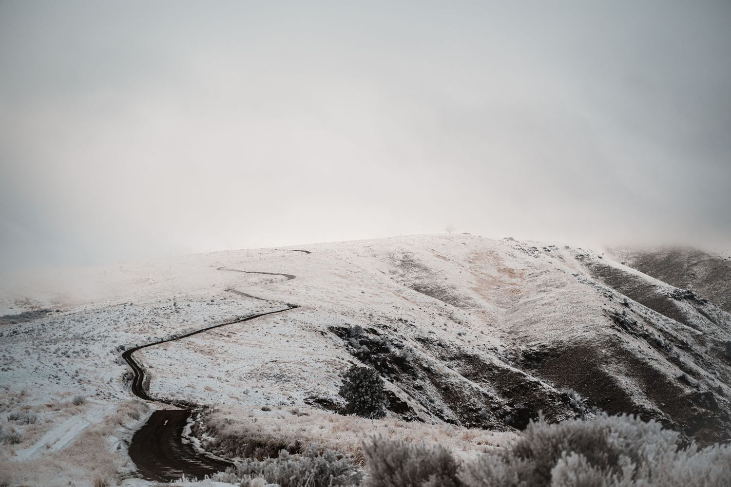 Snow-covered mountain landscape with dramatic cloudy sky.