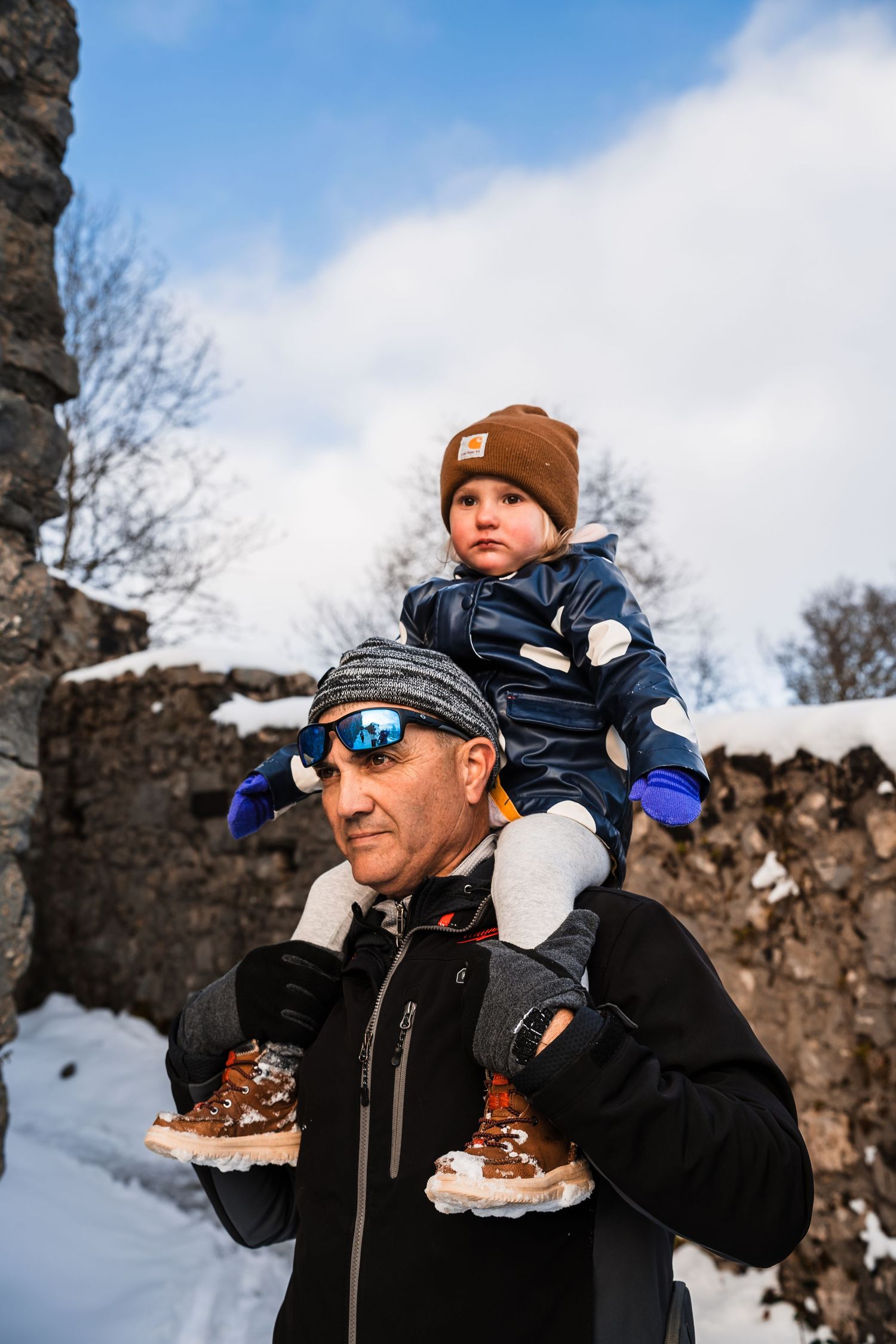 Family enjoying hot beverages outdoors in winter while wearing warm coats and beanies.