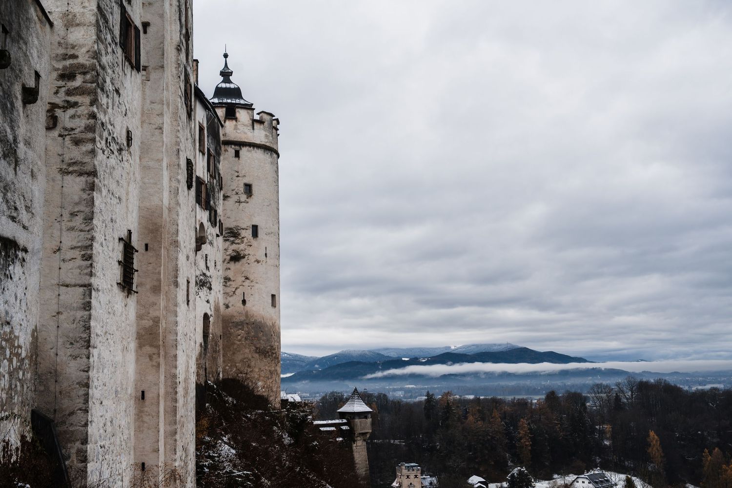 Historic stone fortress walls against a cloudy mountain landscape.