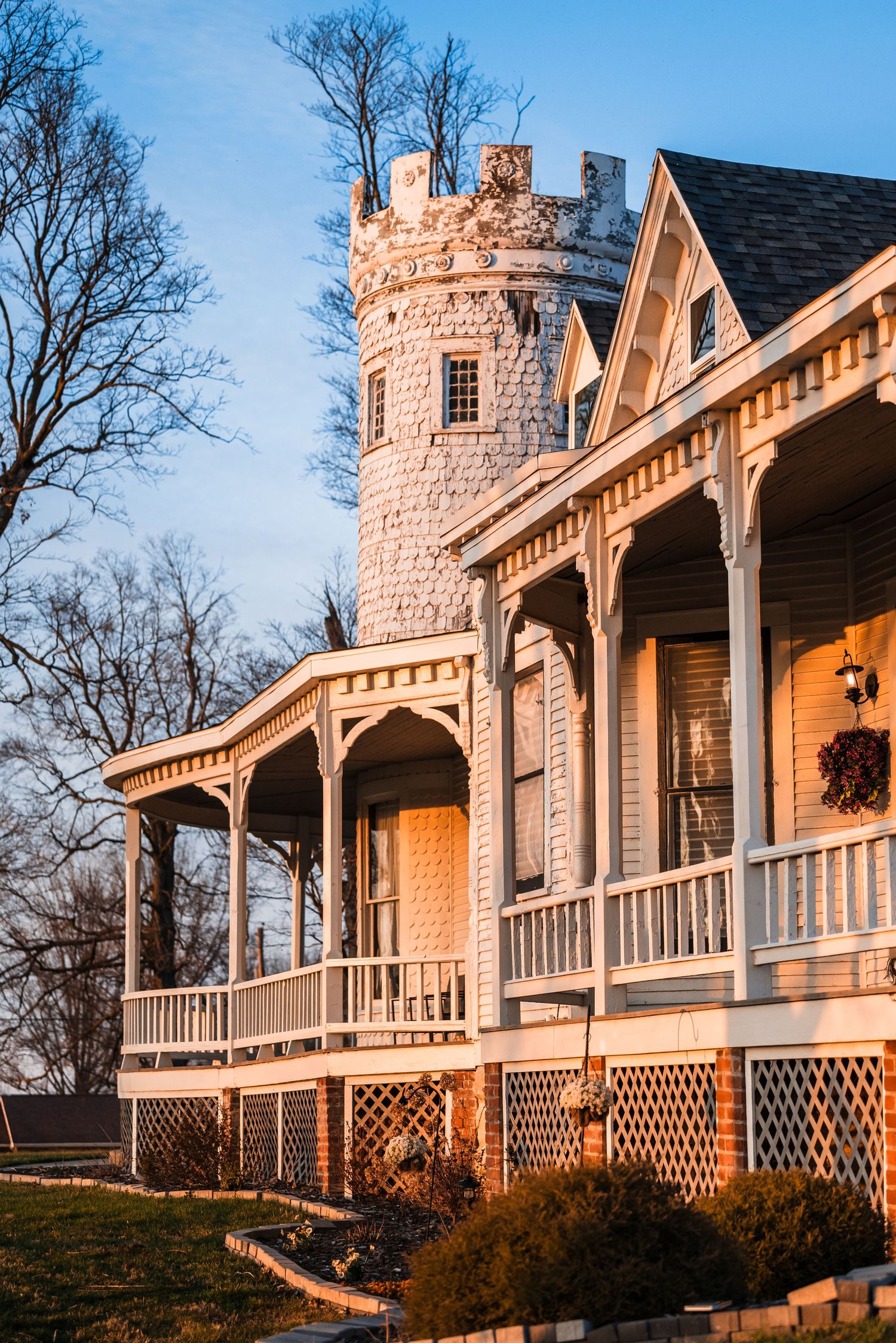 Victorian castle-style wedding venue with tower and wrap-around porch at golden hour.