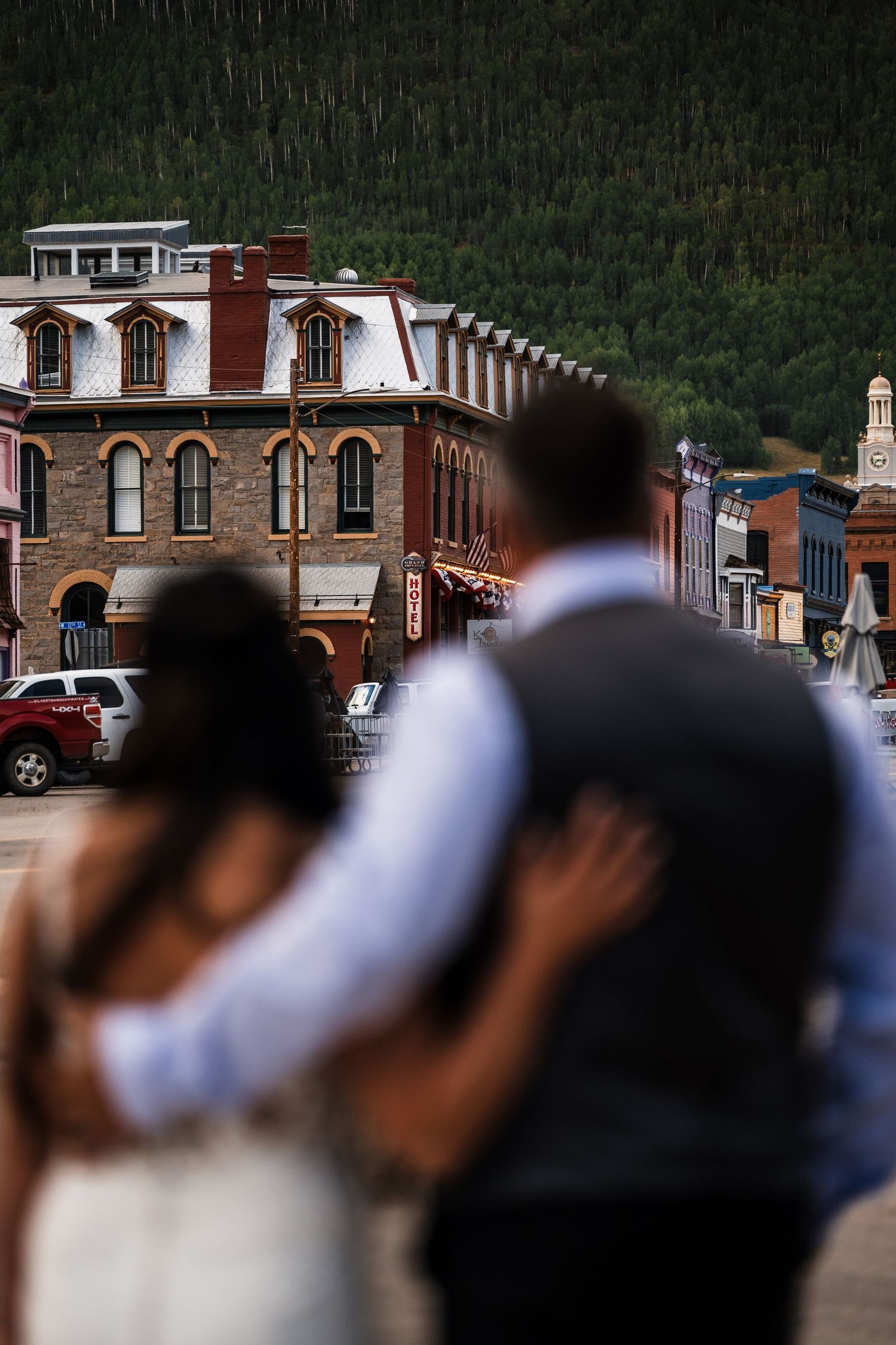 Bride and groom embrace while overlooking a charming historic mountain town street scene.