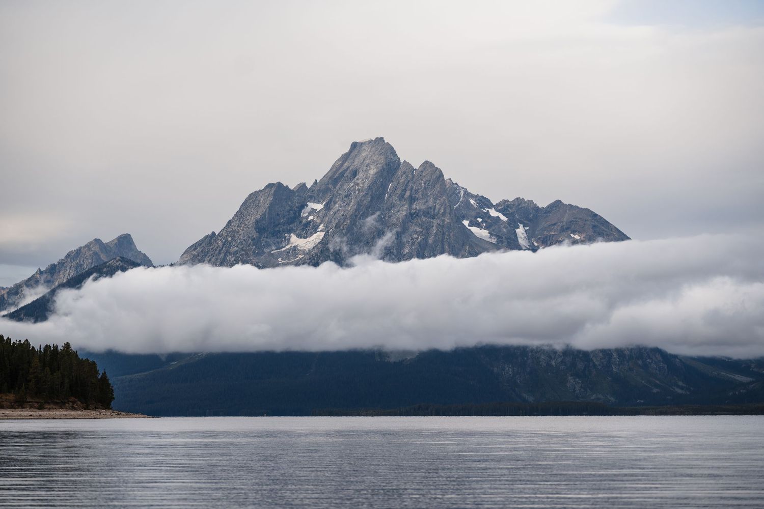 Majestic mountain peaks with snow caps and low-lying clouds in dramatic lighting.