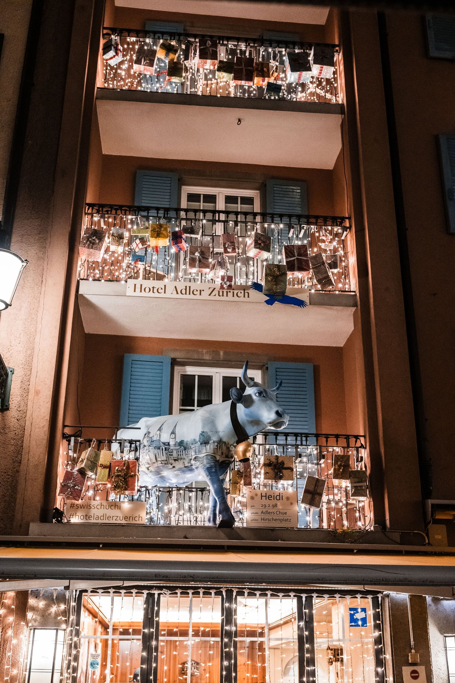 Hotel balconies decorated with numerous photographs and a decorative cow statue on display.