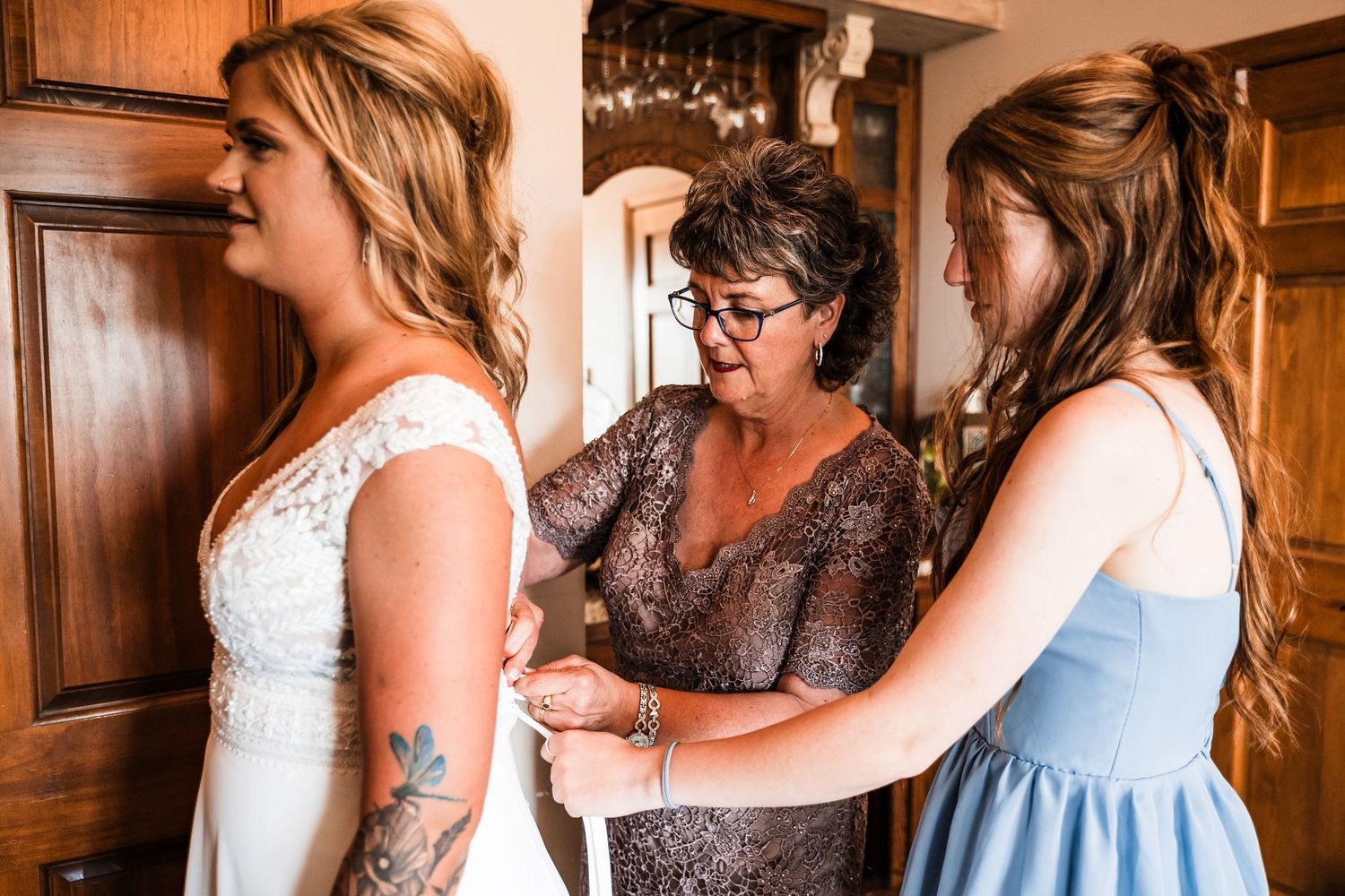 Bridal party helps with wedding preparations in rustic wood-paneled room.