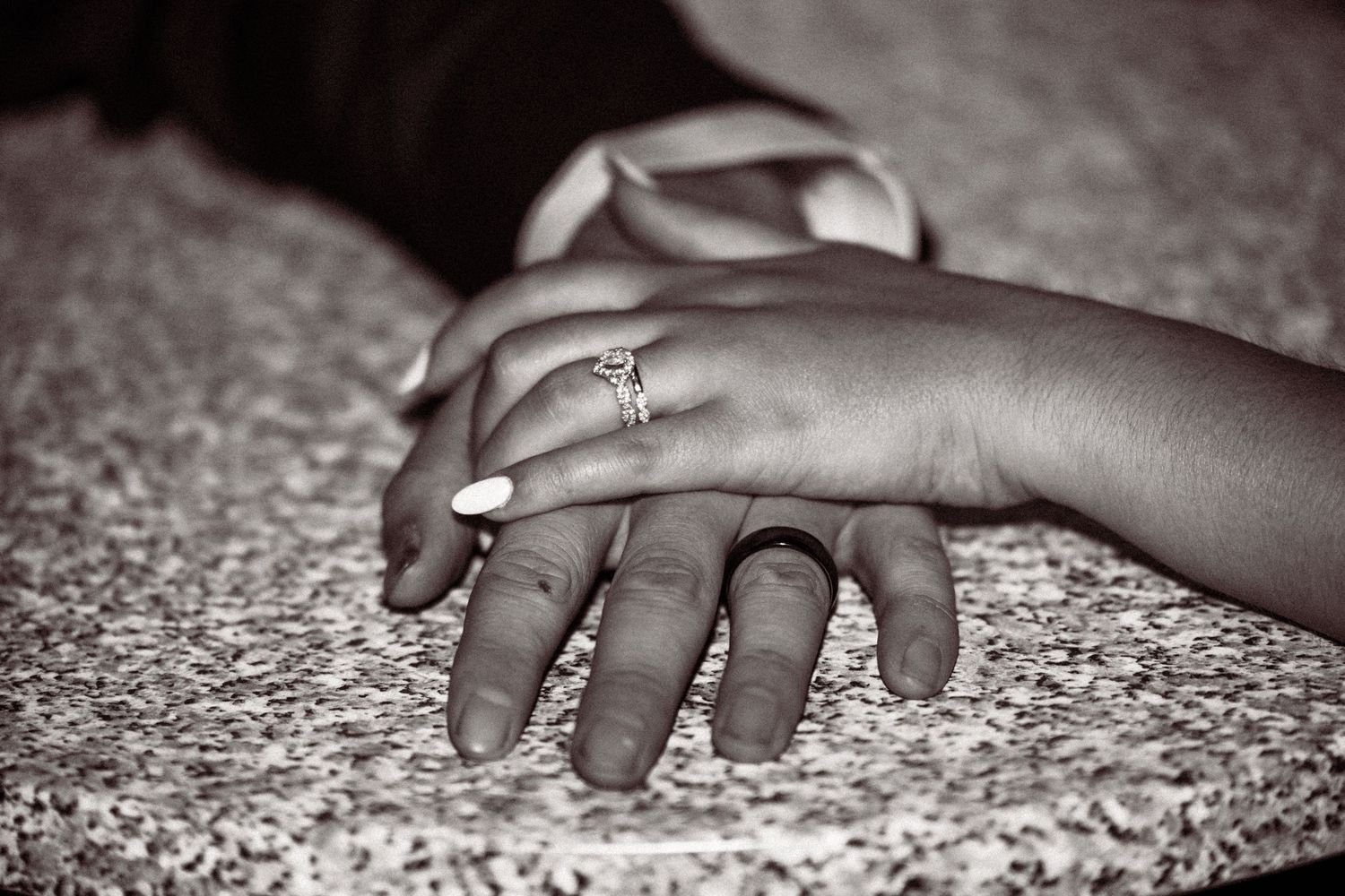 Black and white close-up photograph showing a sequence of hands resting on a textured surface.