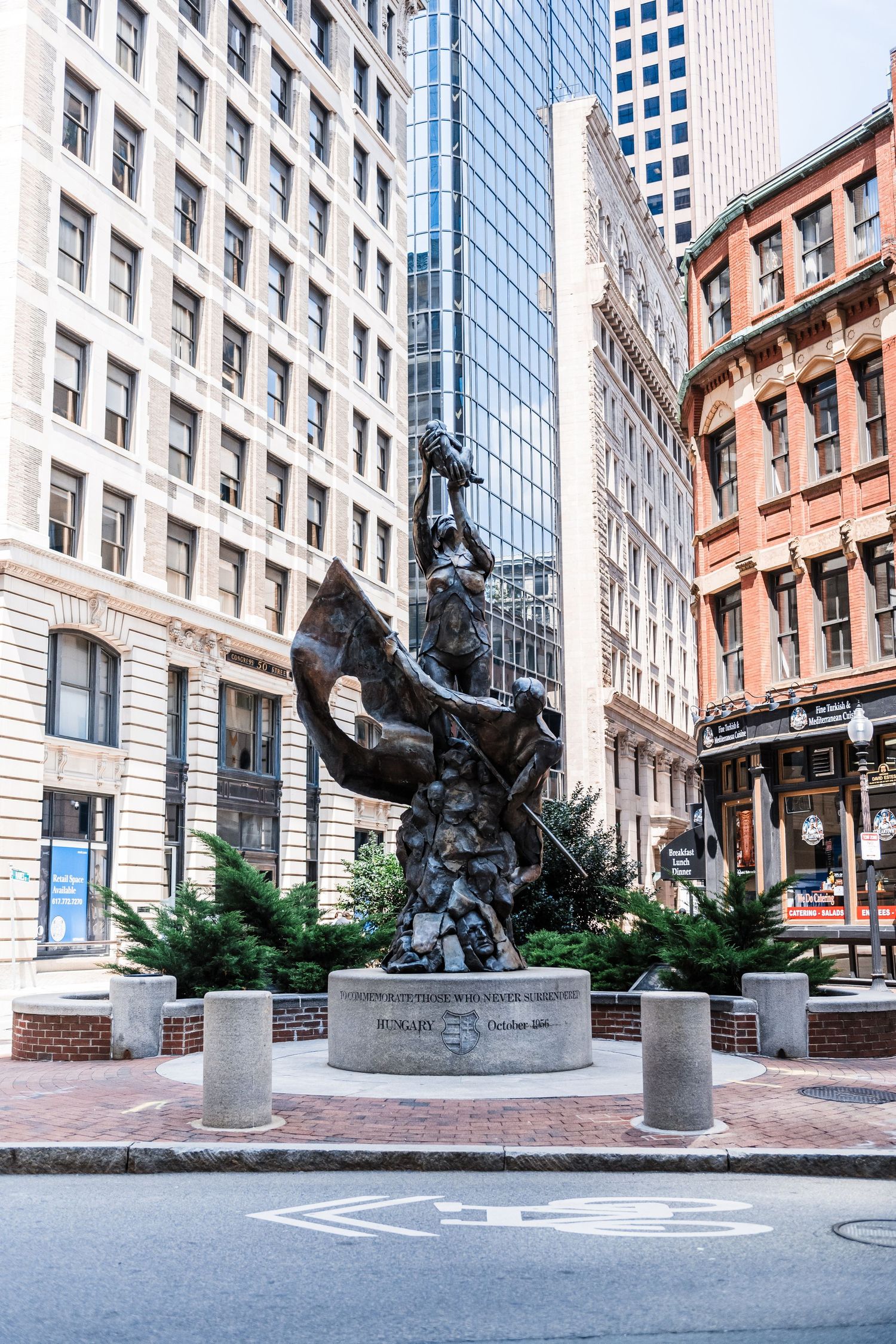 Bronze sculpture in front of historic buildings in downtown Boston with modern skyscrapers in background.
