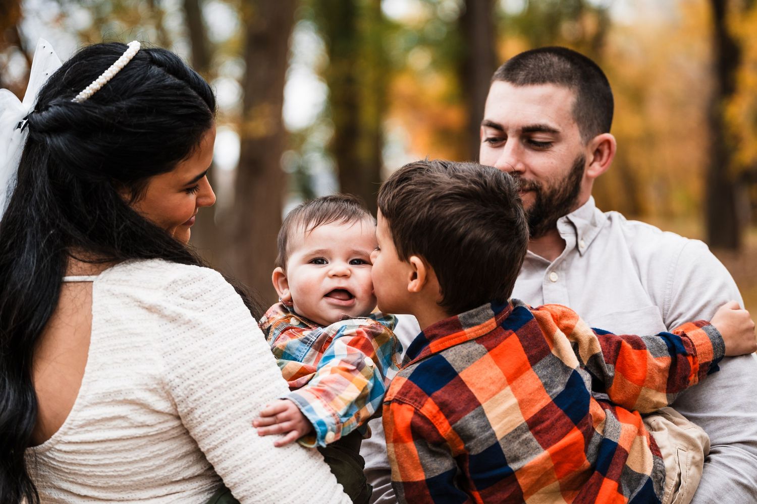 Family shares joyful moment together during autumn photoshoot in wooded setting.