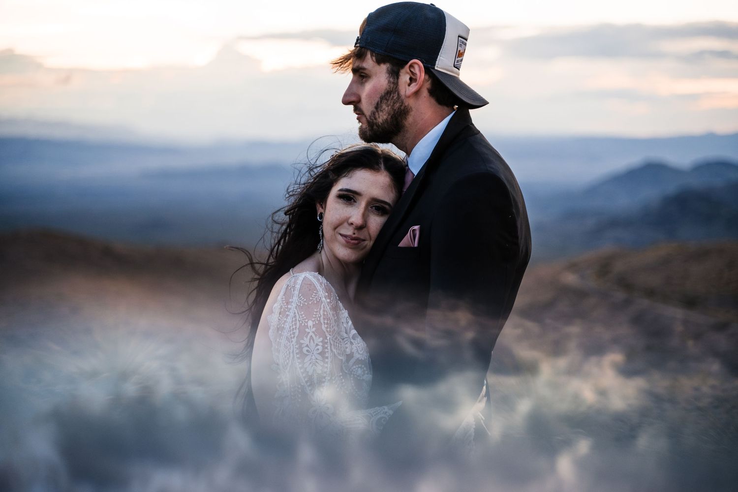 A tender moment shared between a couple on a misty mountain peak at dusk.