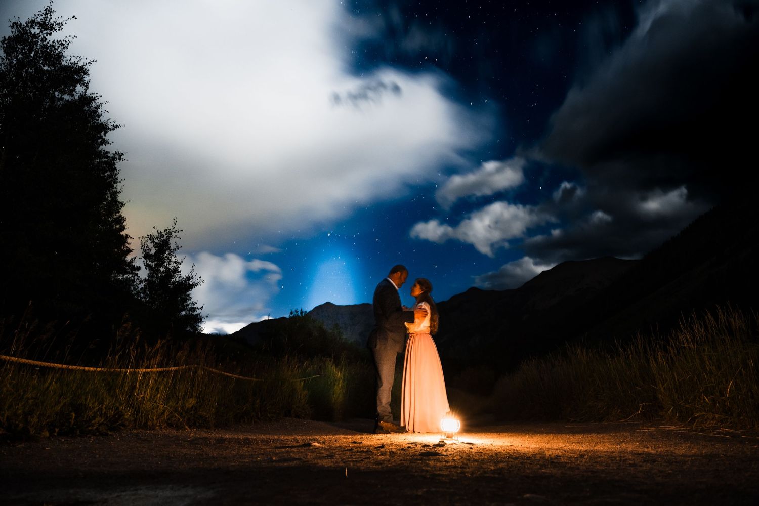 Dramatic nighttime portrait illuminated by single light source in mountain setting.