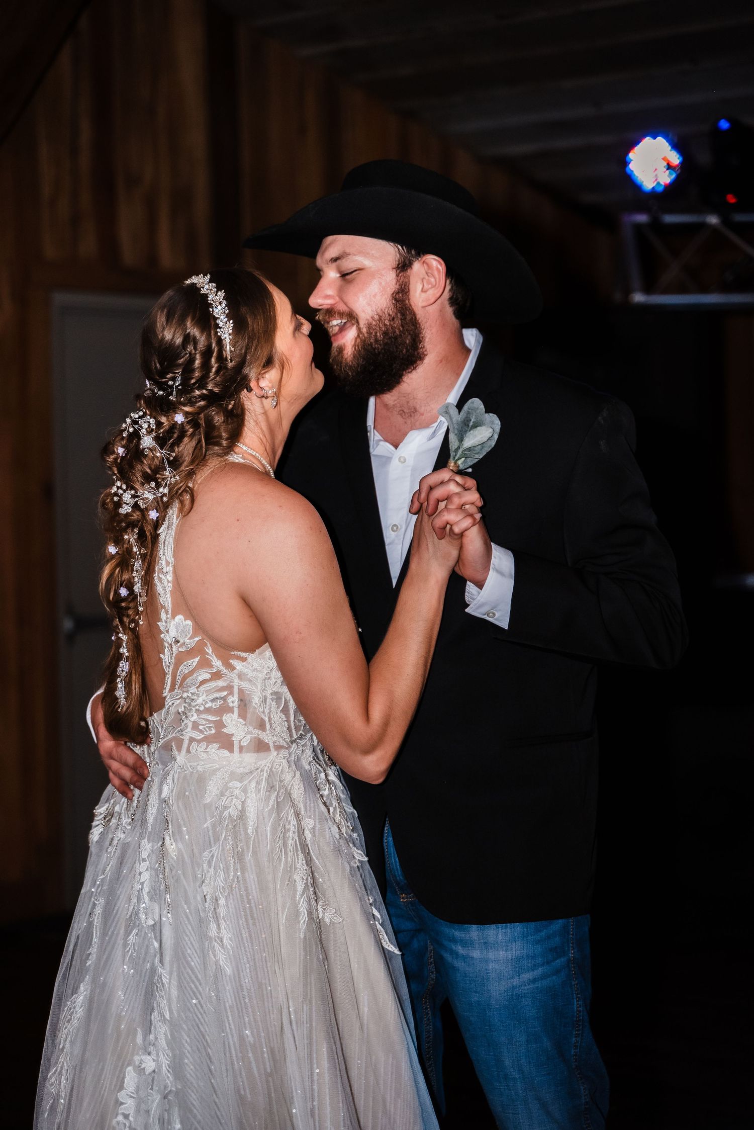 A romantic first dance moment in a rustic barn setting with atmospheric lighting.