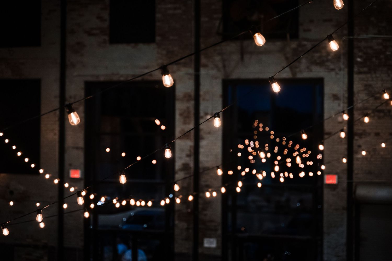 String lights create ambient lighting against dark brick wall at evening event.