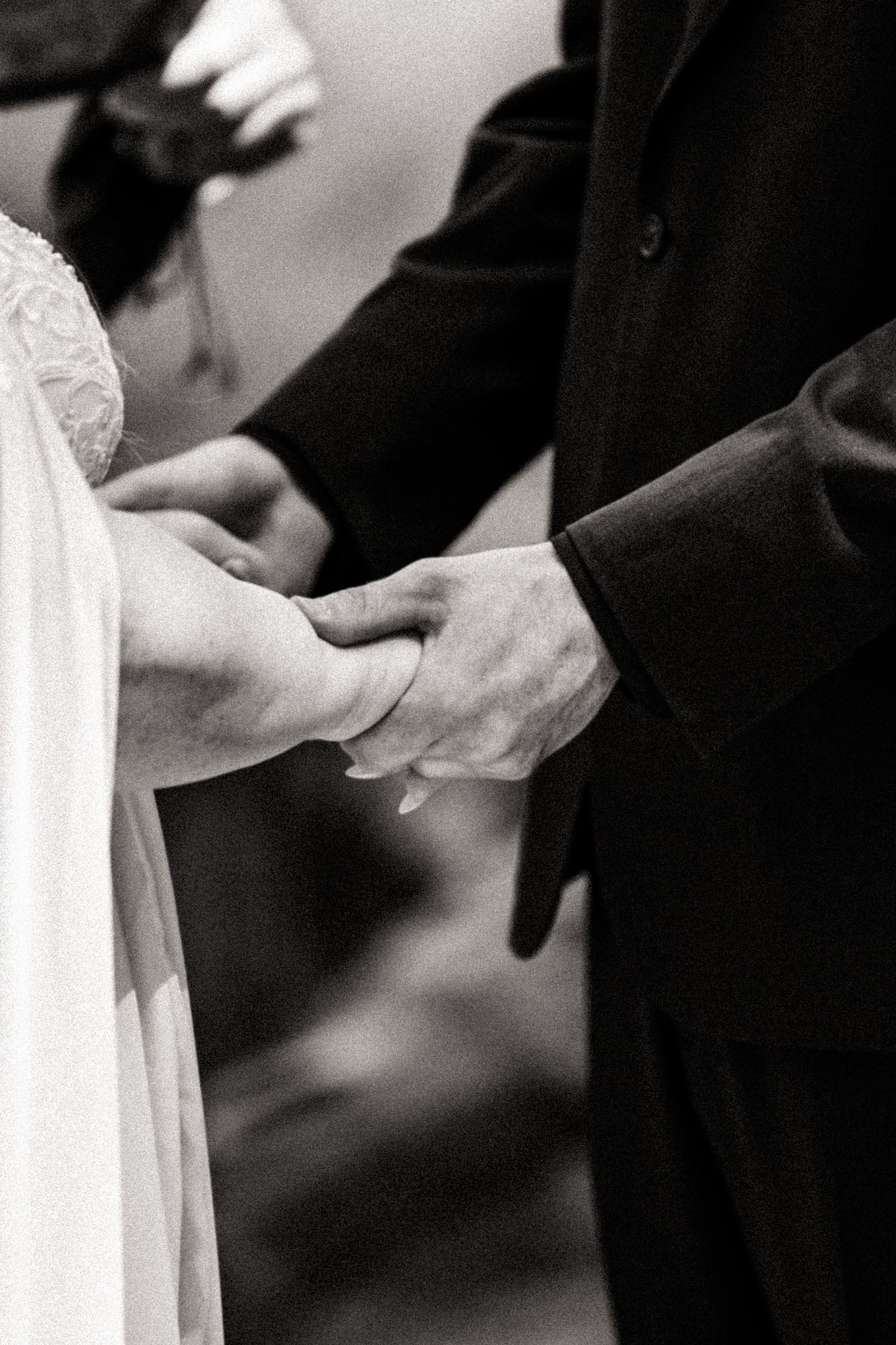 Close-up black and white shots of hands exchanging wedding rings during ceremony.