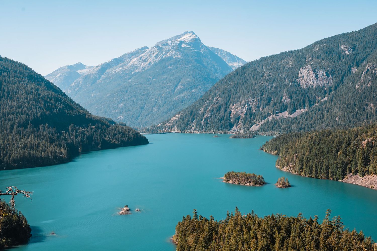 Panoramic aerial view of Diablo Lake with turquoise waters surrounded by forested mountains in North Cascades National Park.