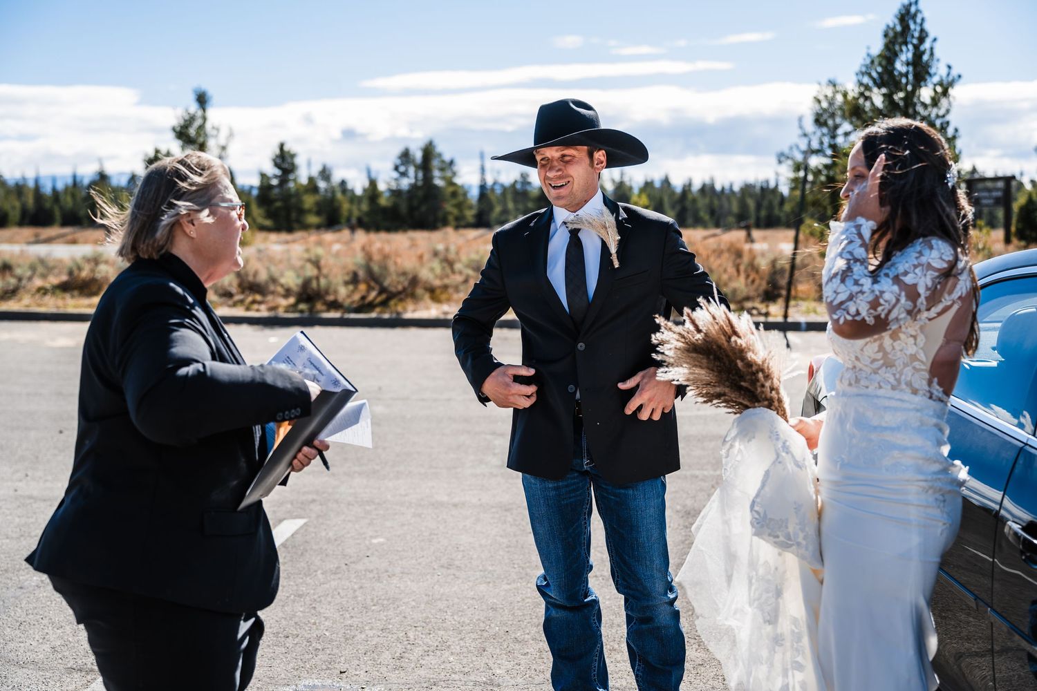 A romantic wedding ceremony takes place outdoors with mountains and evergreen trees in the background.