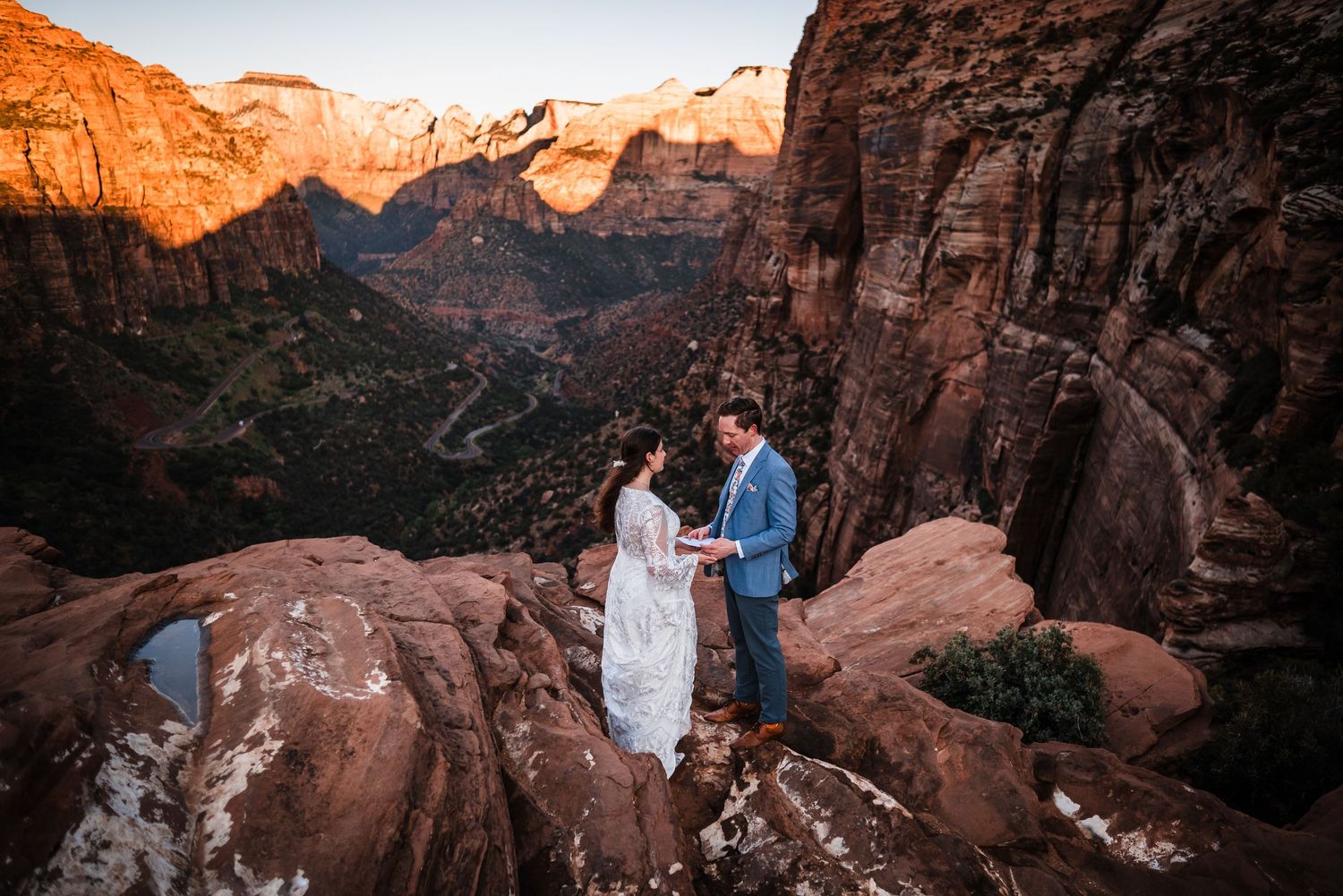 Couple exchanges vows on a rocky overlook at Zion National Park with stunning canyon views at sunset.
