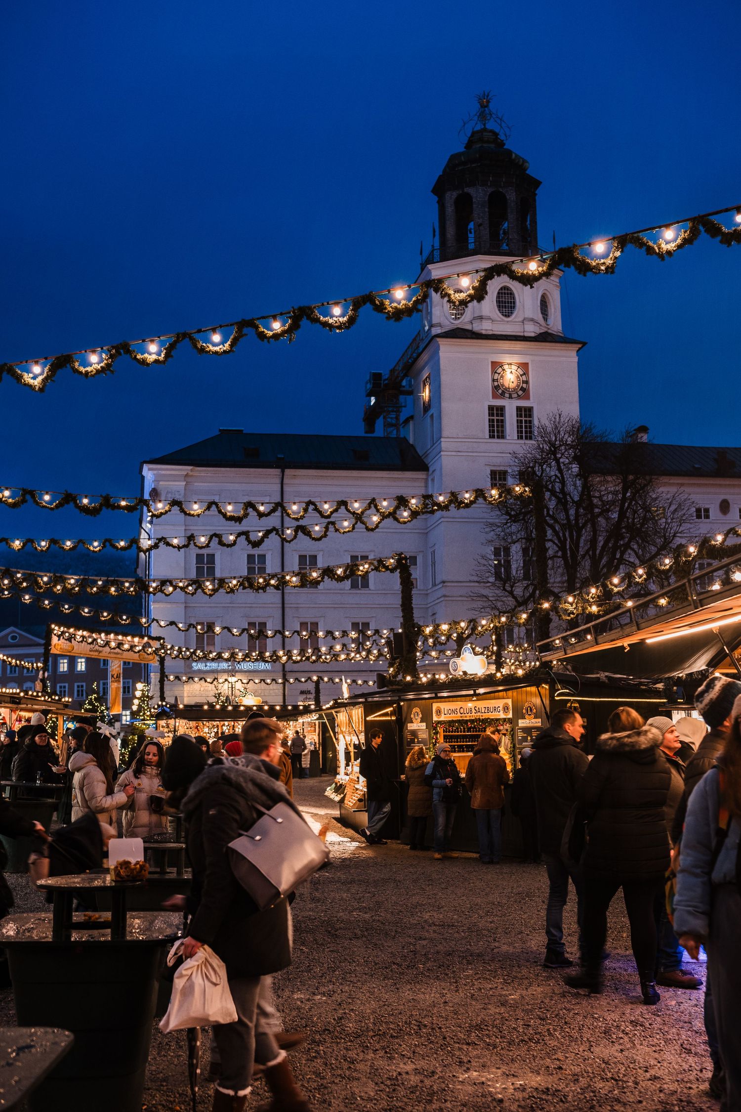 Outdoor evening celebration with string lights illuminating a historic church courtyard during a festive gathering.