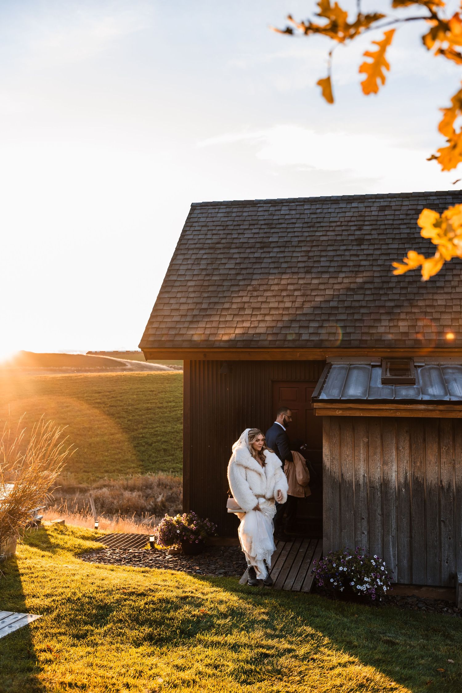 Rustic wooden barn at sunset with golden autumn leaves in the background.